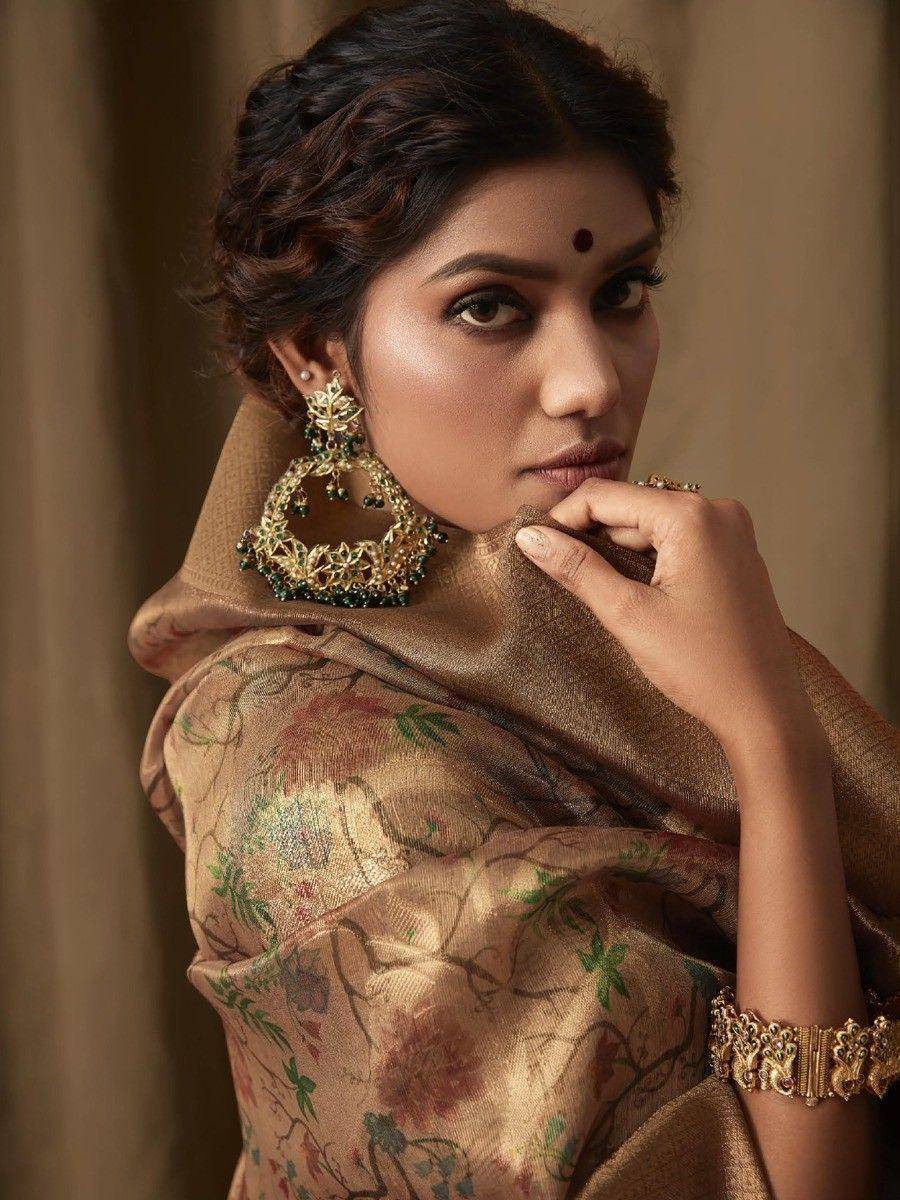 Elegant woman in floral saree with gold jewelry, showcasing traditional Indian ethnic wear.