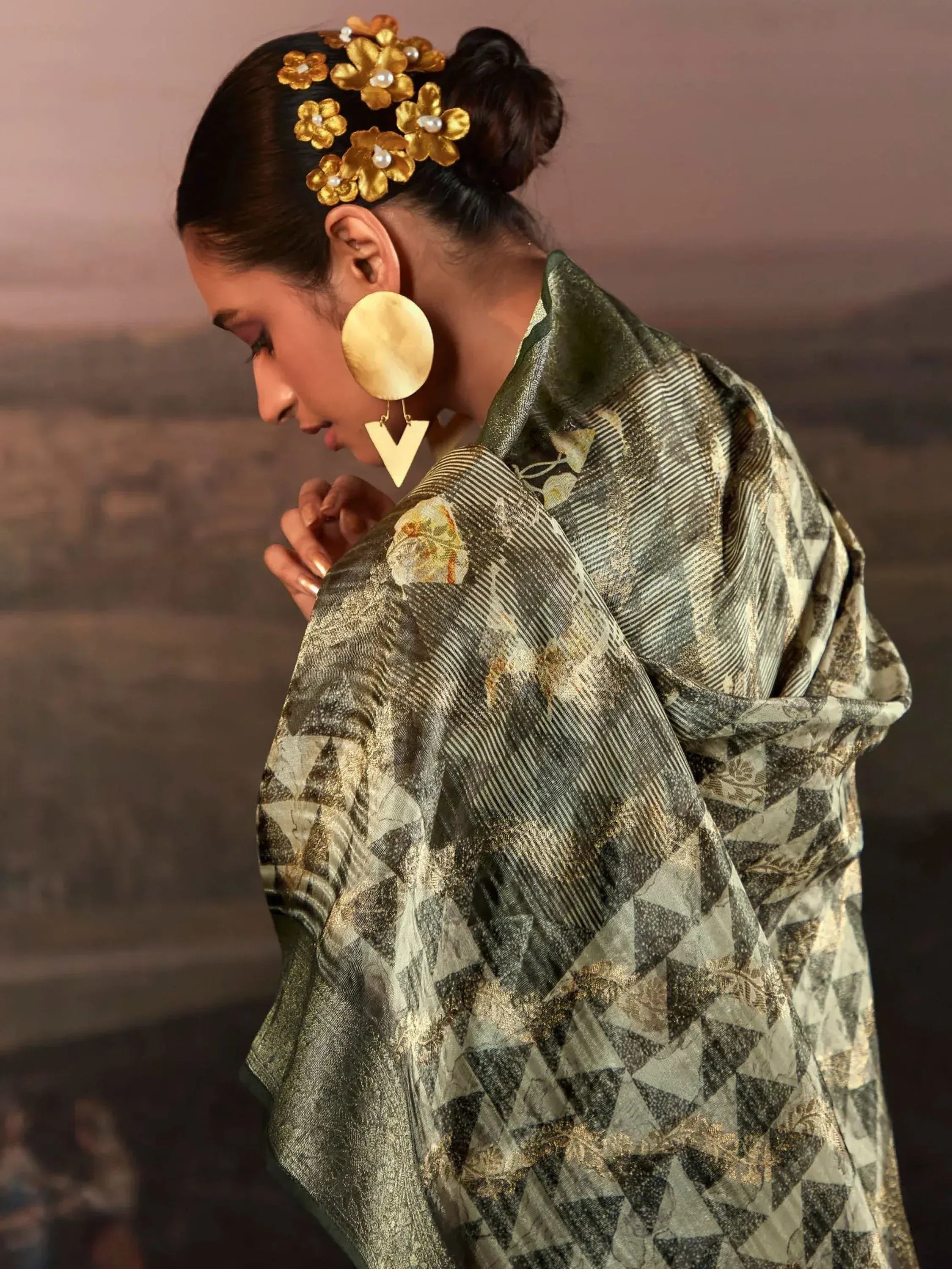 Woman in olive green ethnic gown with gold floral hair accessories and statement earrings