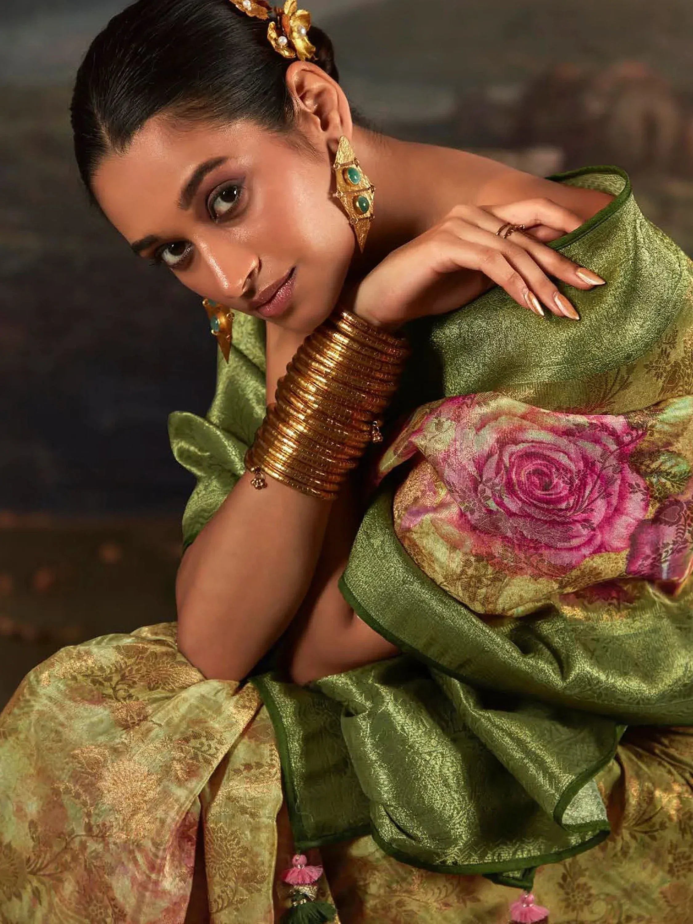 Elegant woman in green floral saree with gold jewelry, showcasing traditional Indian ethnic wear.