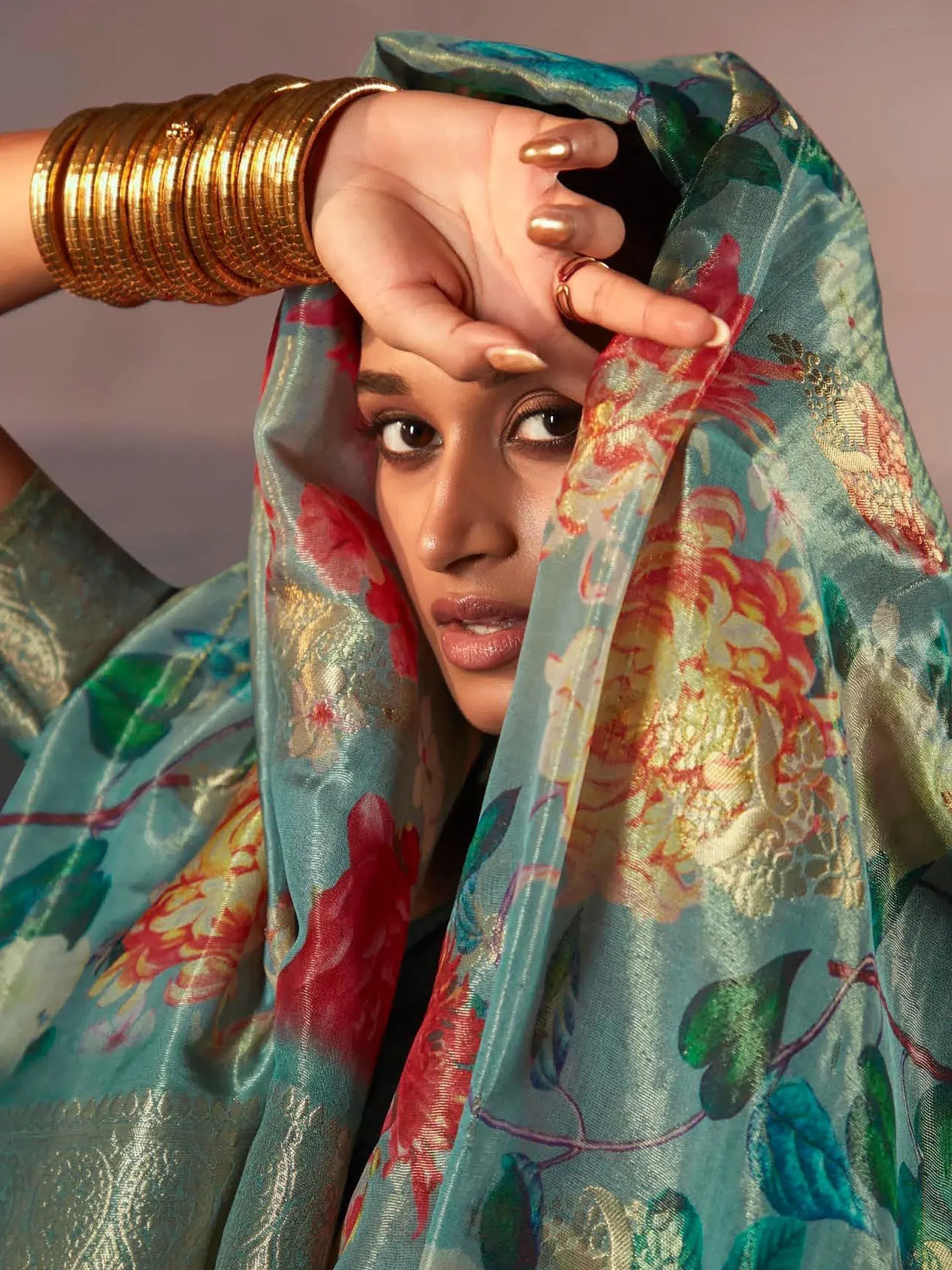 Woman in floral ethnic saree with gold bangles, showcasing Indian designer wear