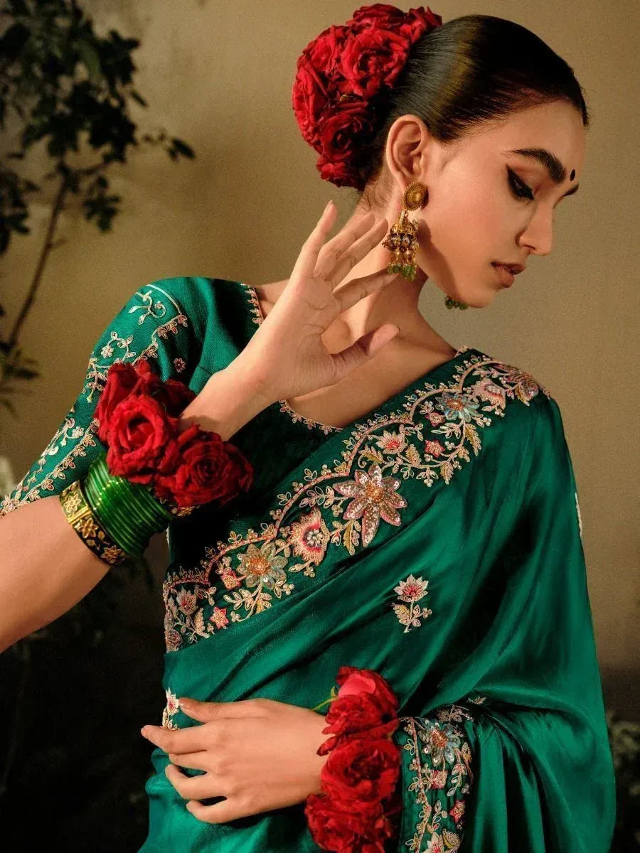 Emerald green embroidered saree with floral details, red rose accessories, and gold jewelry for Indian ethnic wear