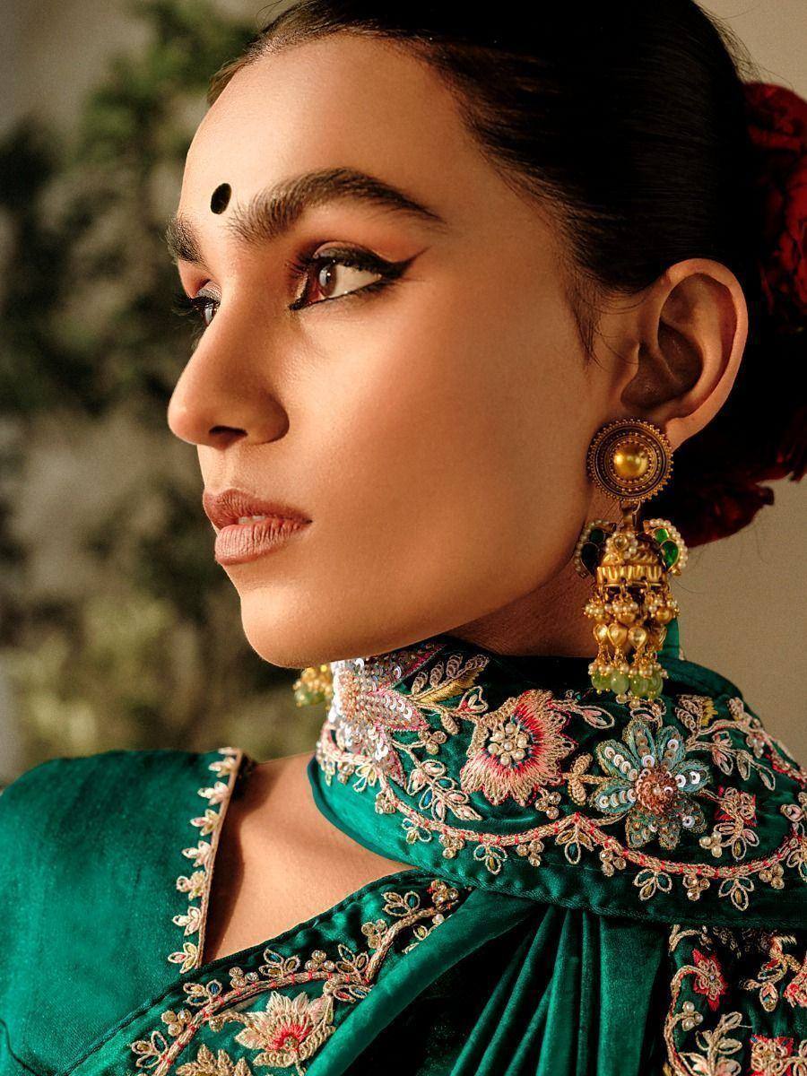 Emerald green embroidered ethnic gown with floral detailing and gold jhumka earrings