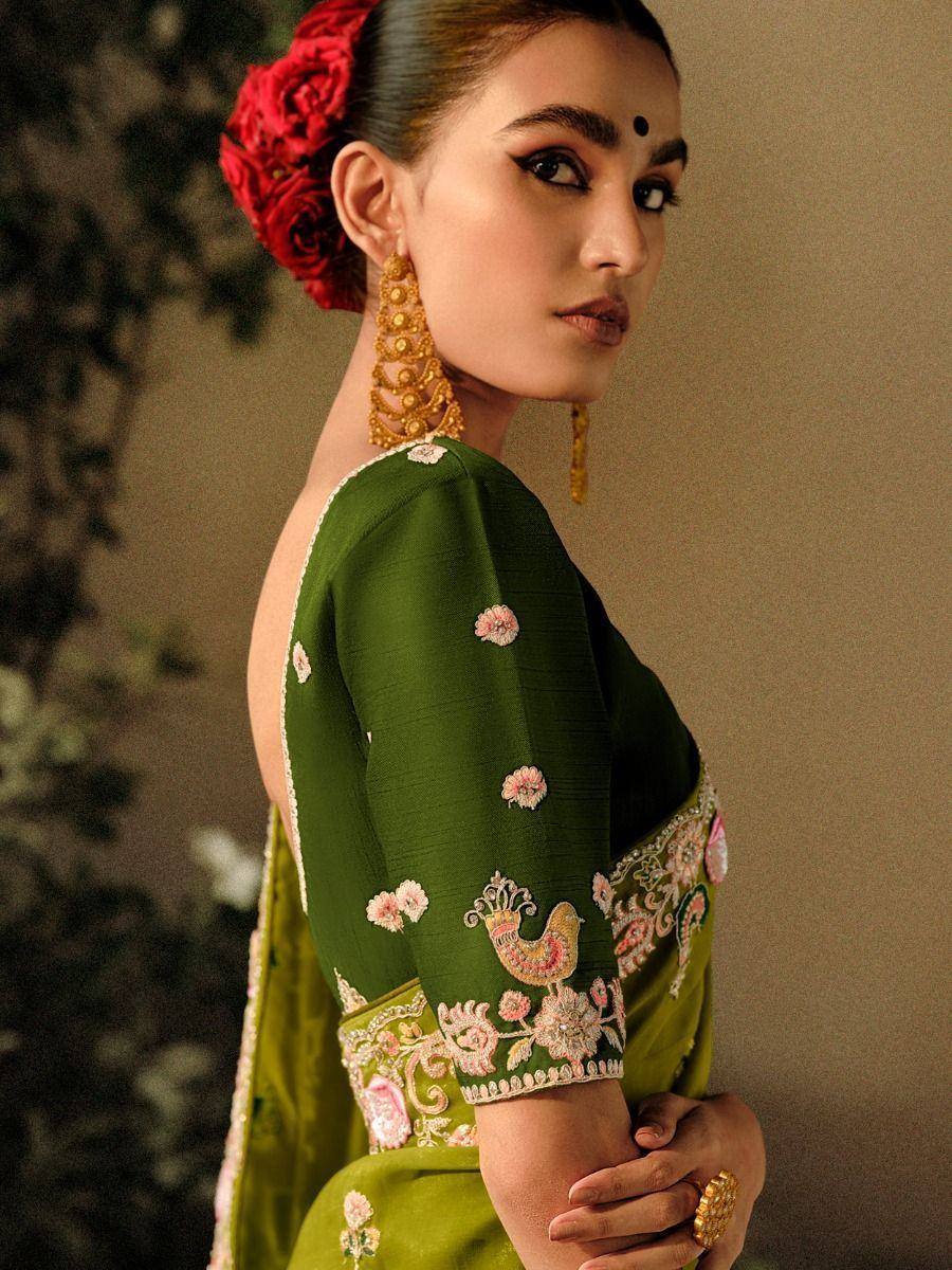Green embroidered saree with floral and peacock motifs, gold jewelry, red rose hair accessory