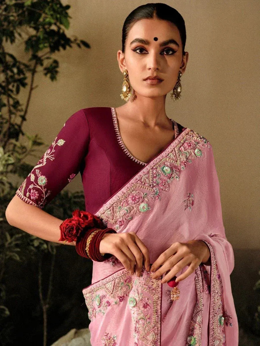 Pink embroidered saree with maroon blouse, floral detailing, and traditional Indian jewelry