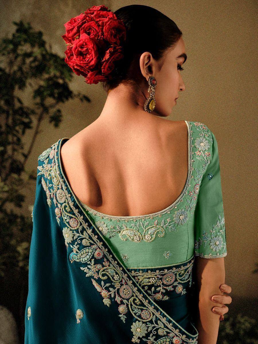 Elegant green embroidered saree with floral detailing and red rose hair accessory