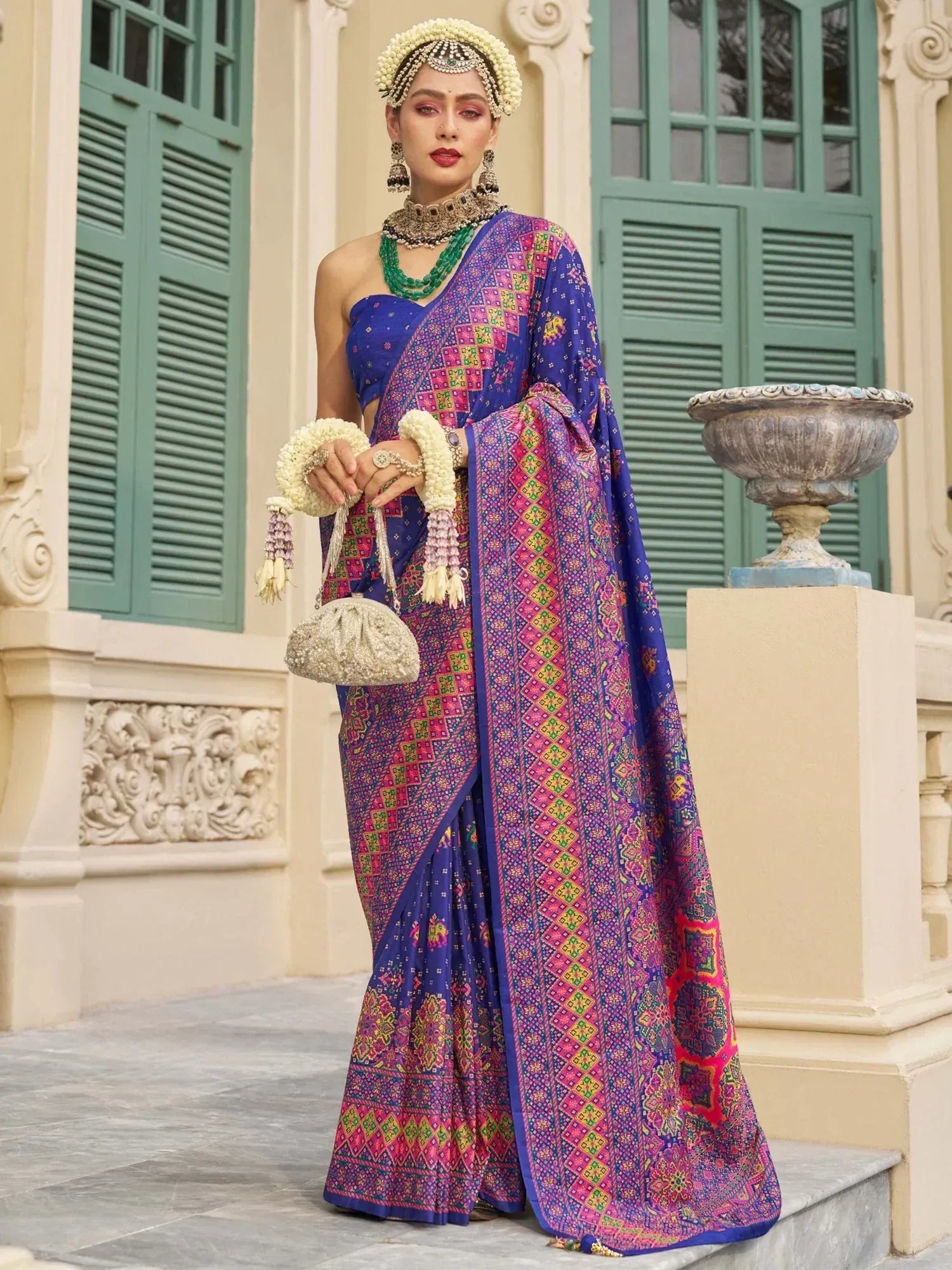 Woman in vibrant blue and pink printed saree with floral jewelry, perfect for Indian ethnic occasions