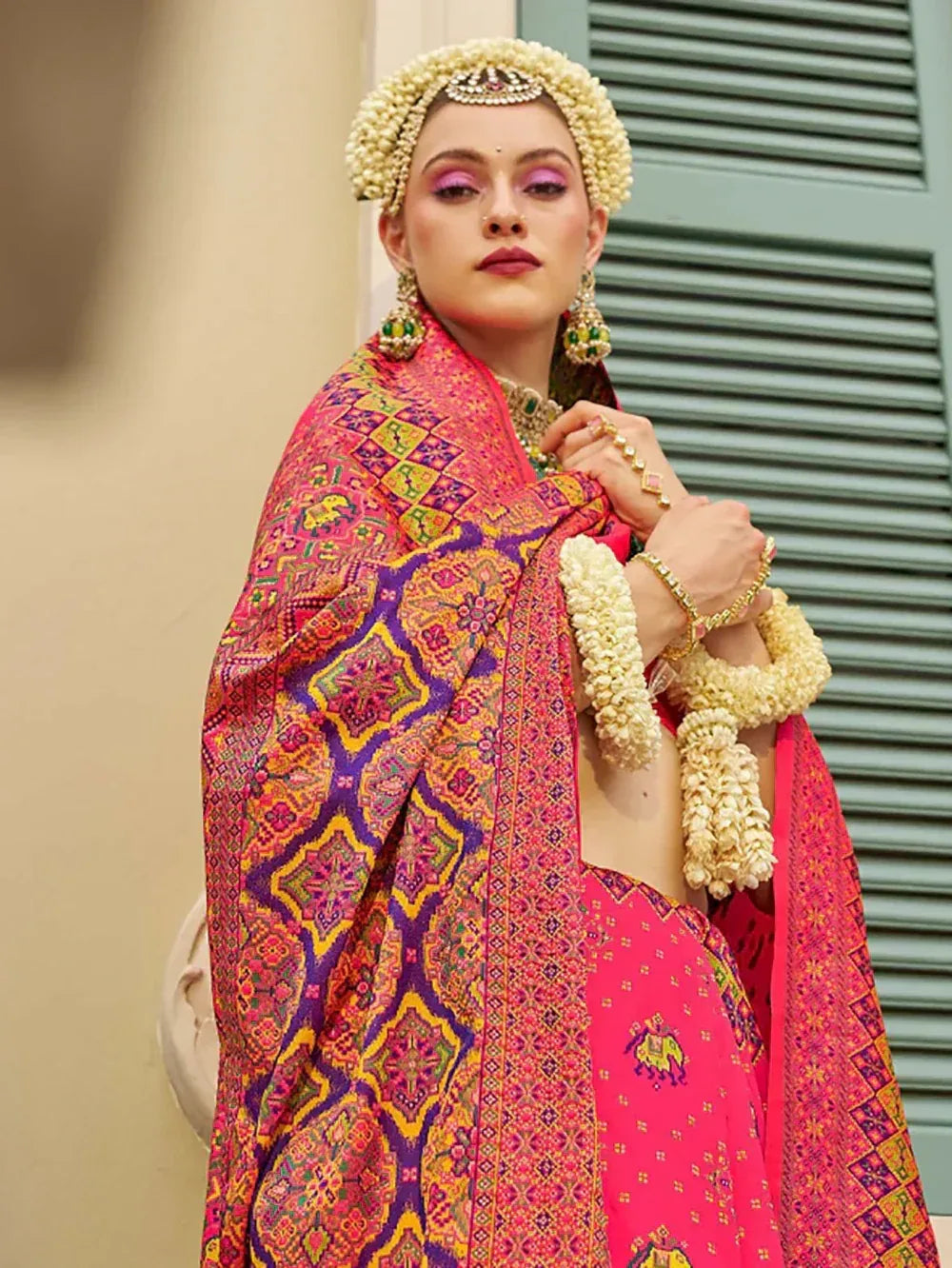 Vibrant pink lehenga choli with intricate geometric print, floral jewelry, and traditional Indian bridal accessories