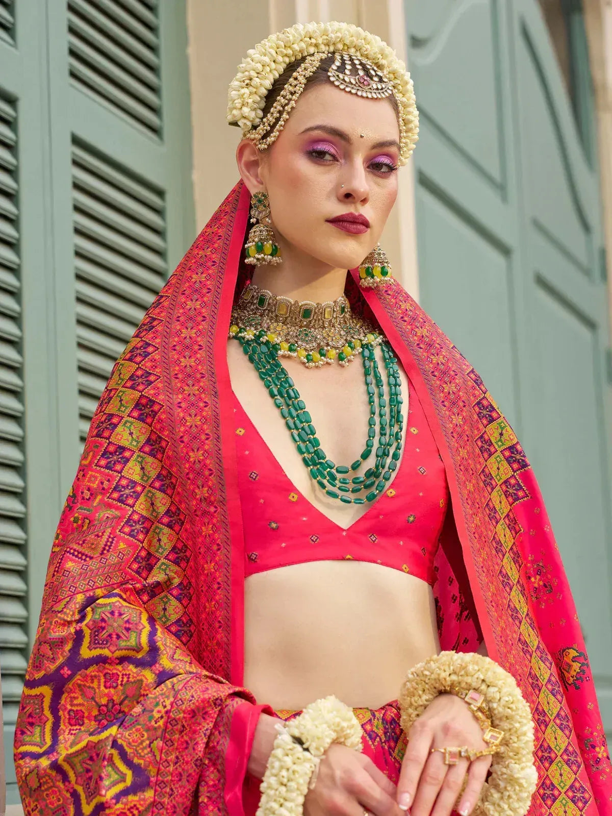 Vibrant pink lehenga choli with floral jewelry and traditional Indian bridal accessories