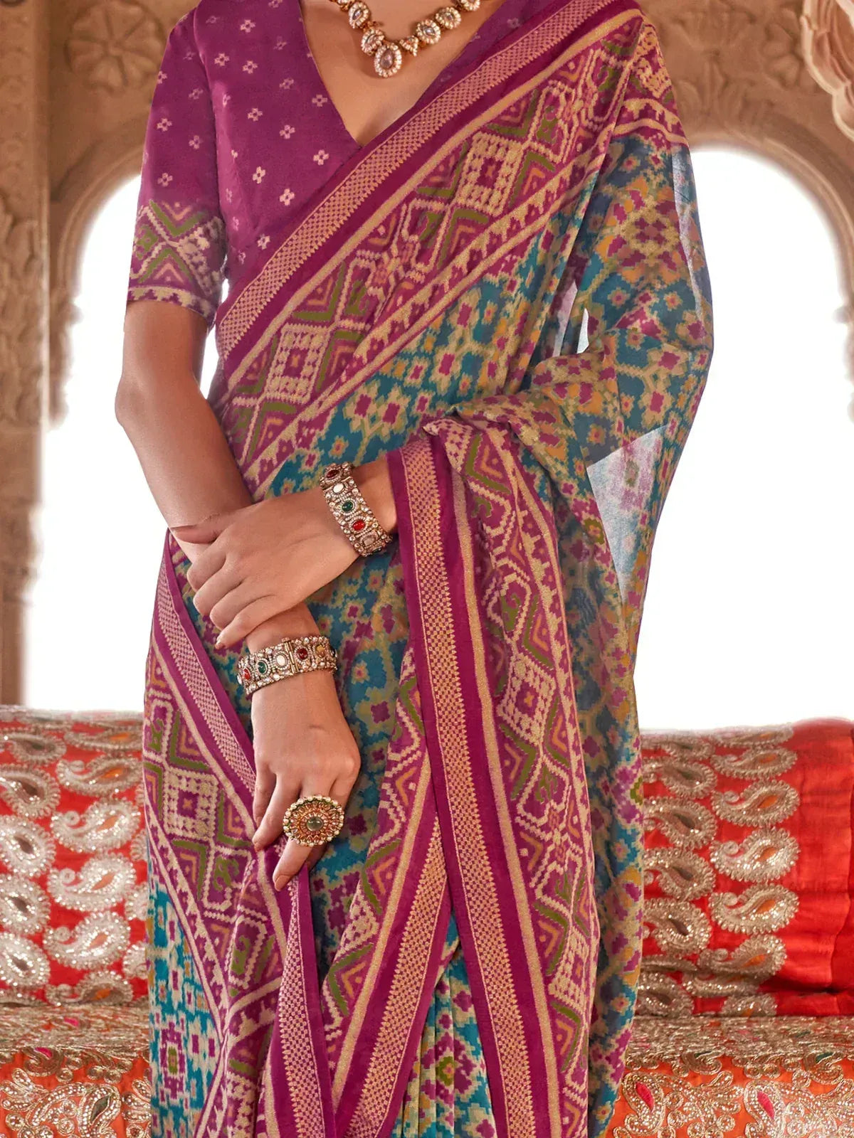 Purple and teal printed saree with geometric border, paired with ethnic jewelry and blouse