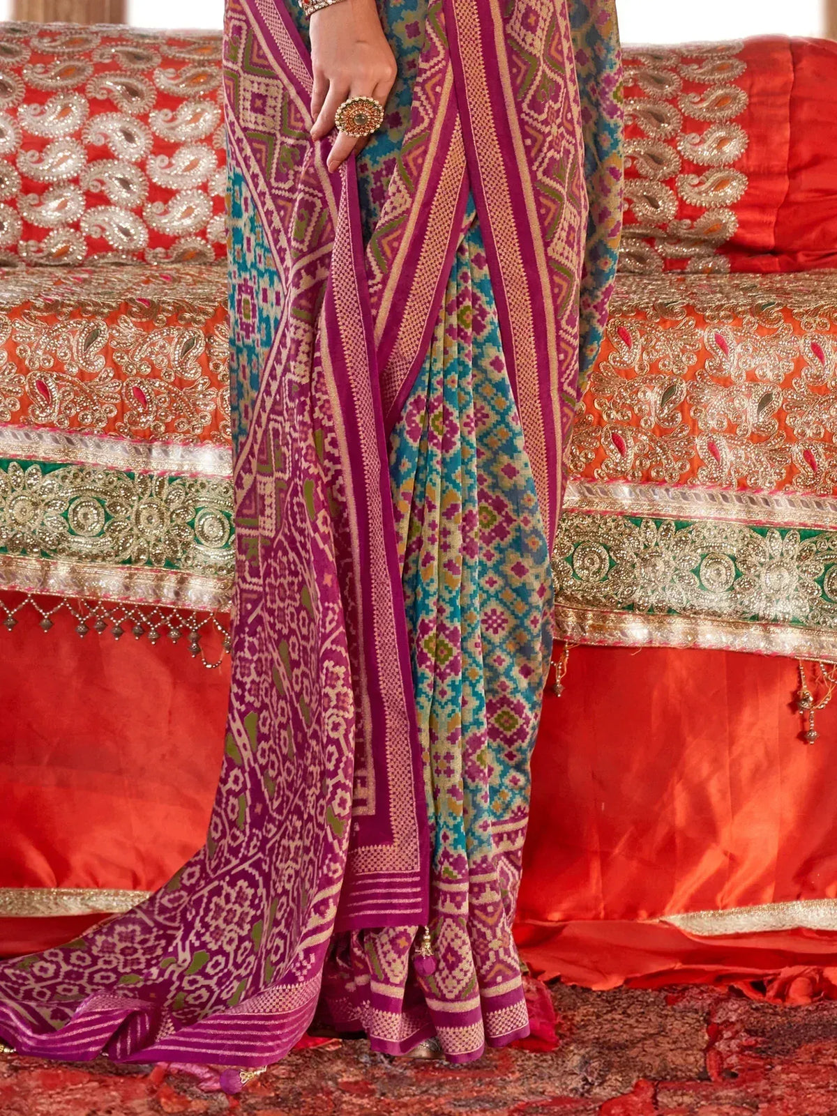 Vibrant purple and teal printed saree with intricate geometric patterns, paired with ornate jewelry, ideal for ethnic occasions.