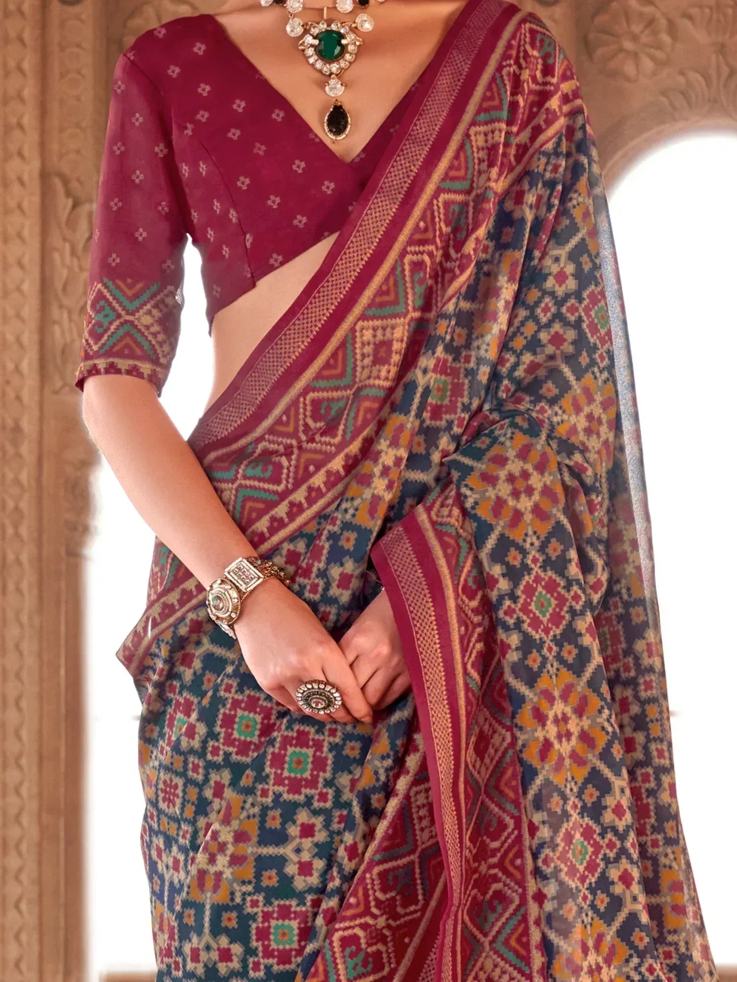 Elegant maroon and blue printed saree with geometric patterns, paired with matching blouse and traditional jewelry