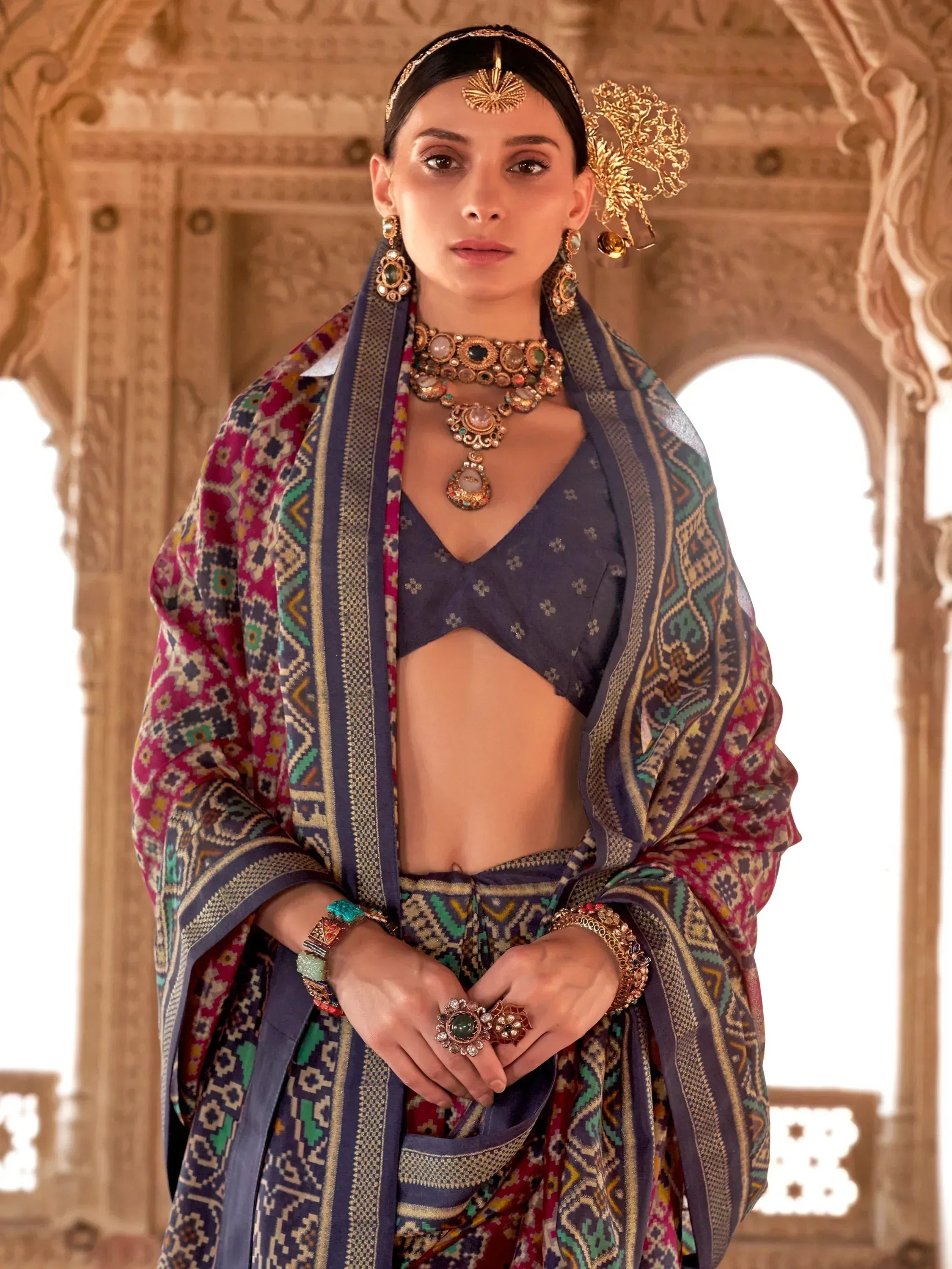 Woman in traditional Indian ethnic wear with intricate jewelry and patterned dupatta, styled for festive occasions.