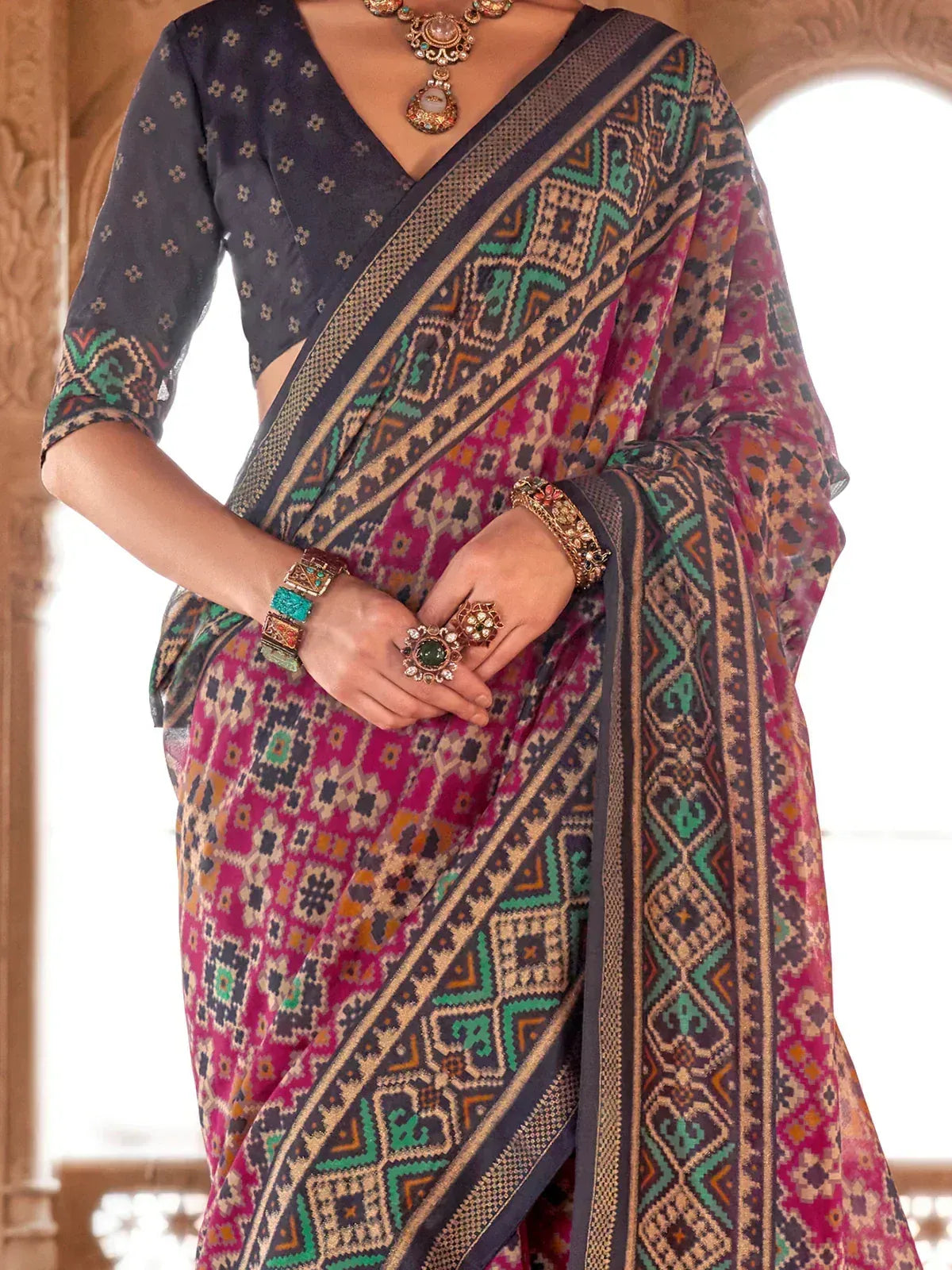Woman in vibrant ethnic saree with geometric print, paired with designer blouse and traditional jewelry
