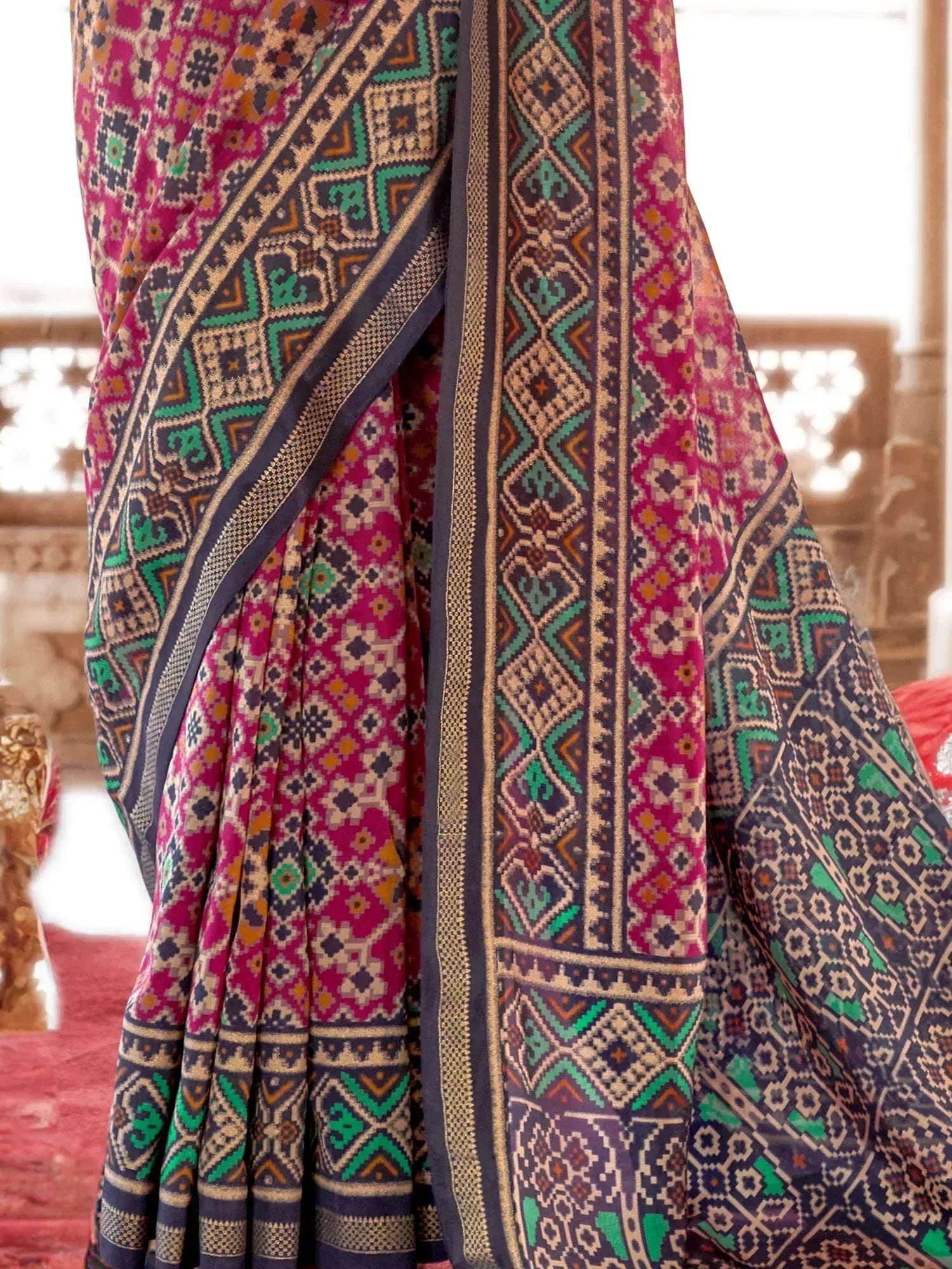 Vibrant ethnic saree with geometric patterns in magenta, teal, and navy, perfect for traditional Indian wear.