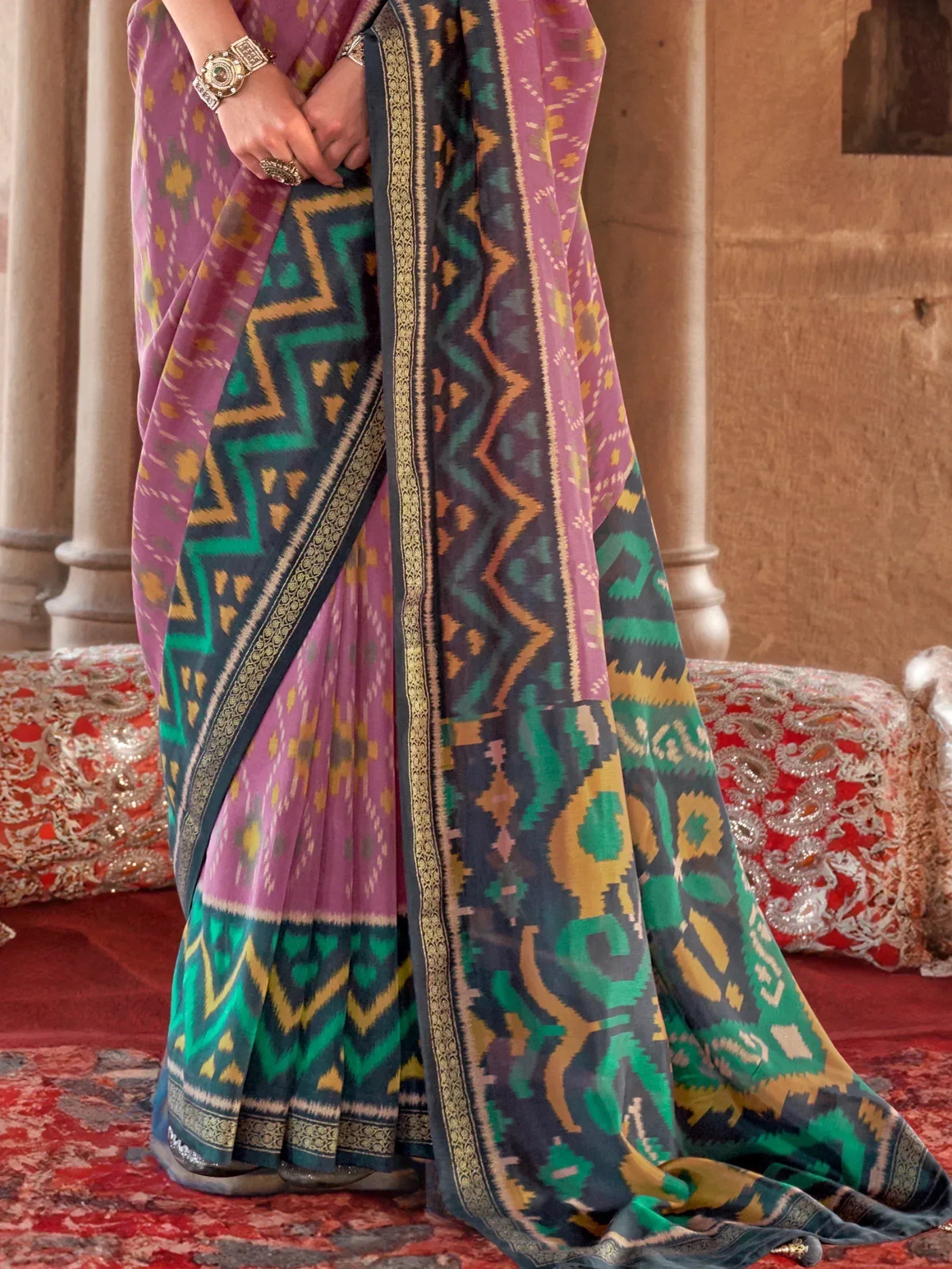 Purple and green ikat patterned saree with gold border, styled with traditional jewelry for ethnic wear.