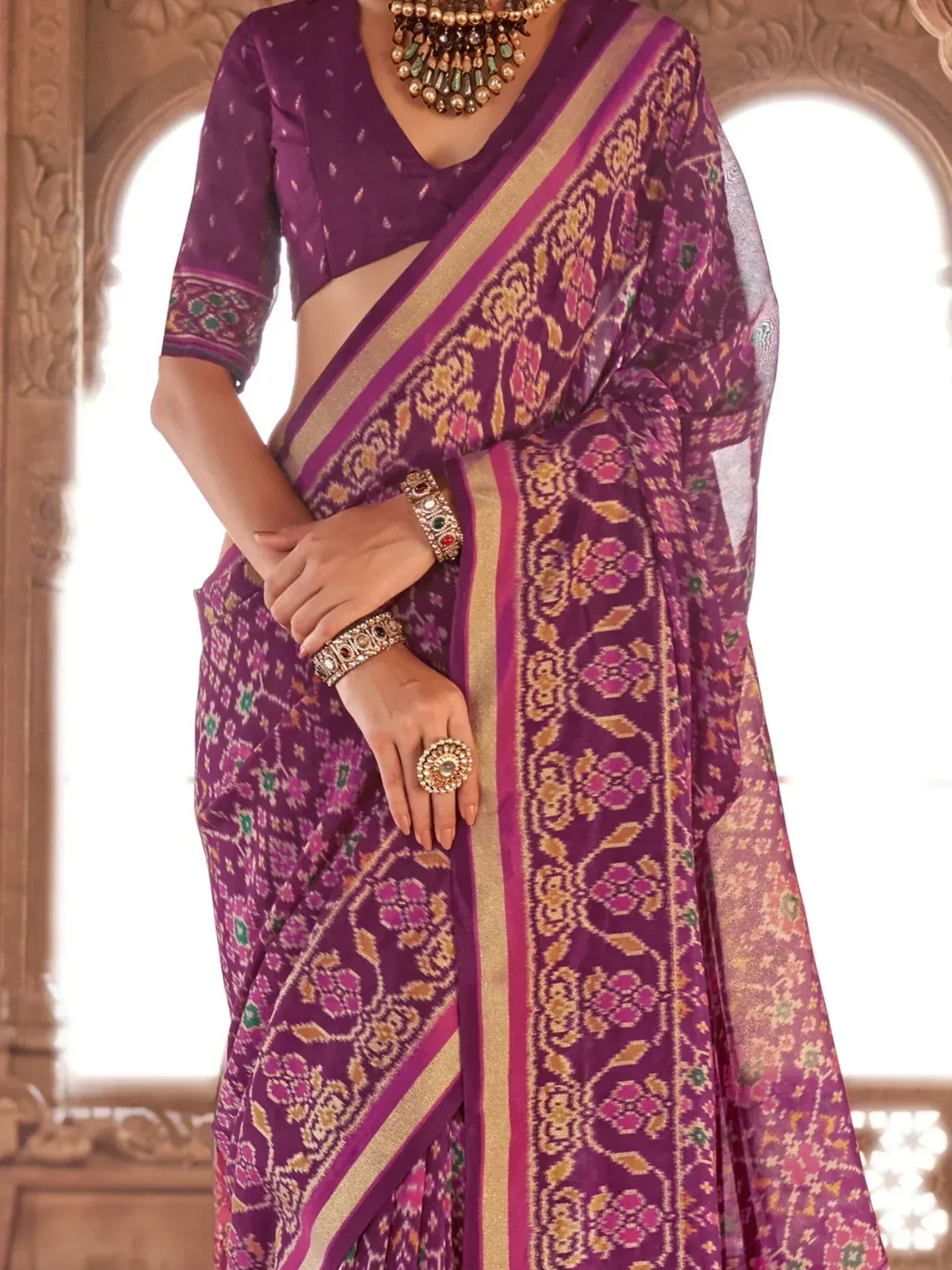 Purple floral Ikat saree with gold border, paired with matching blouse and traditional jewelry