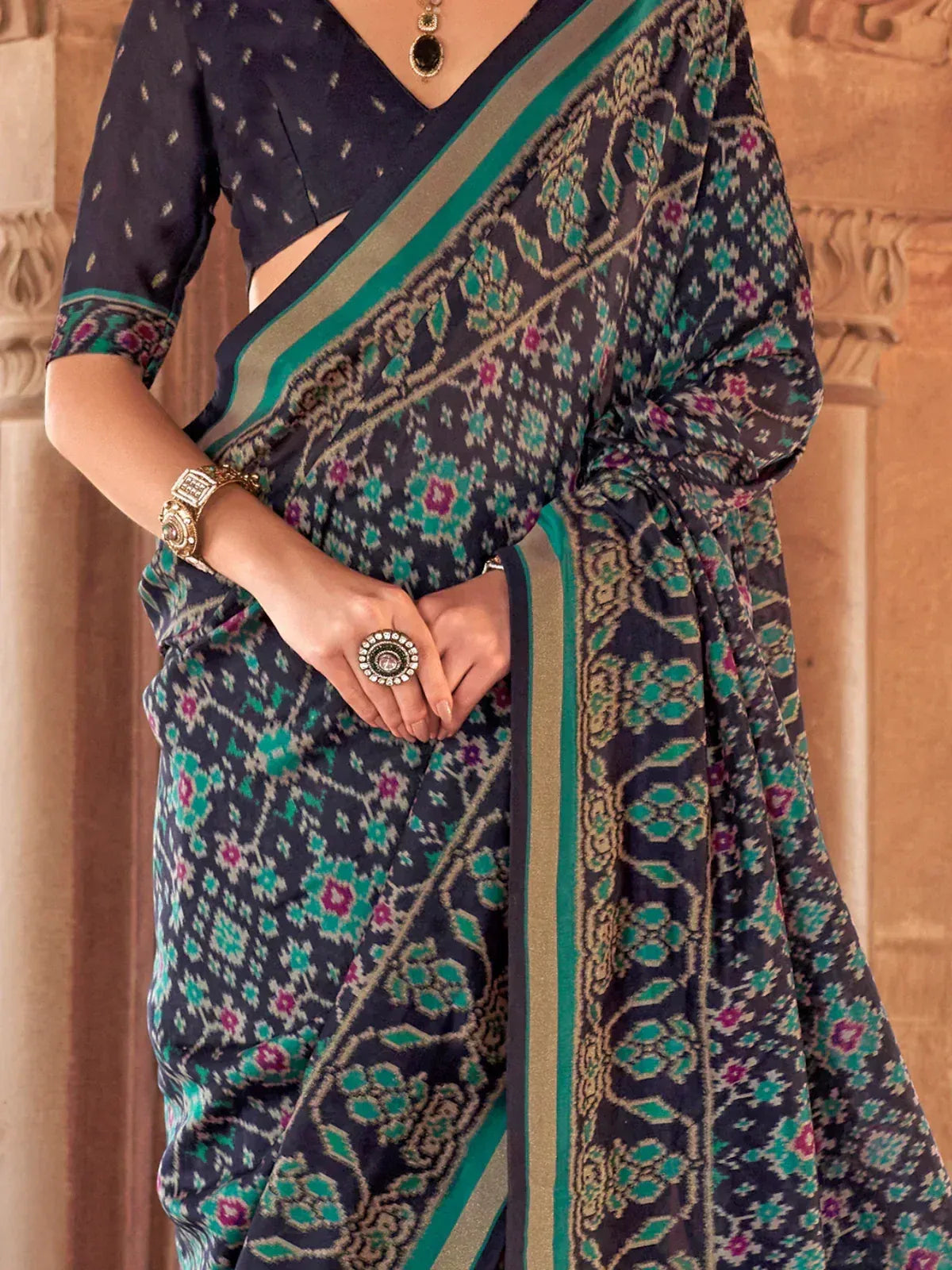 Navy blue saree with teal and pink ikat print, paired with matching blouse and gold jewelry