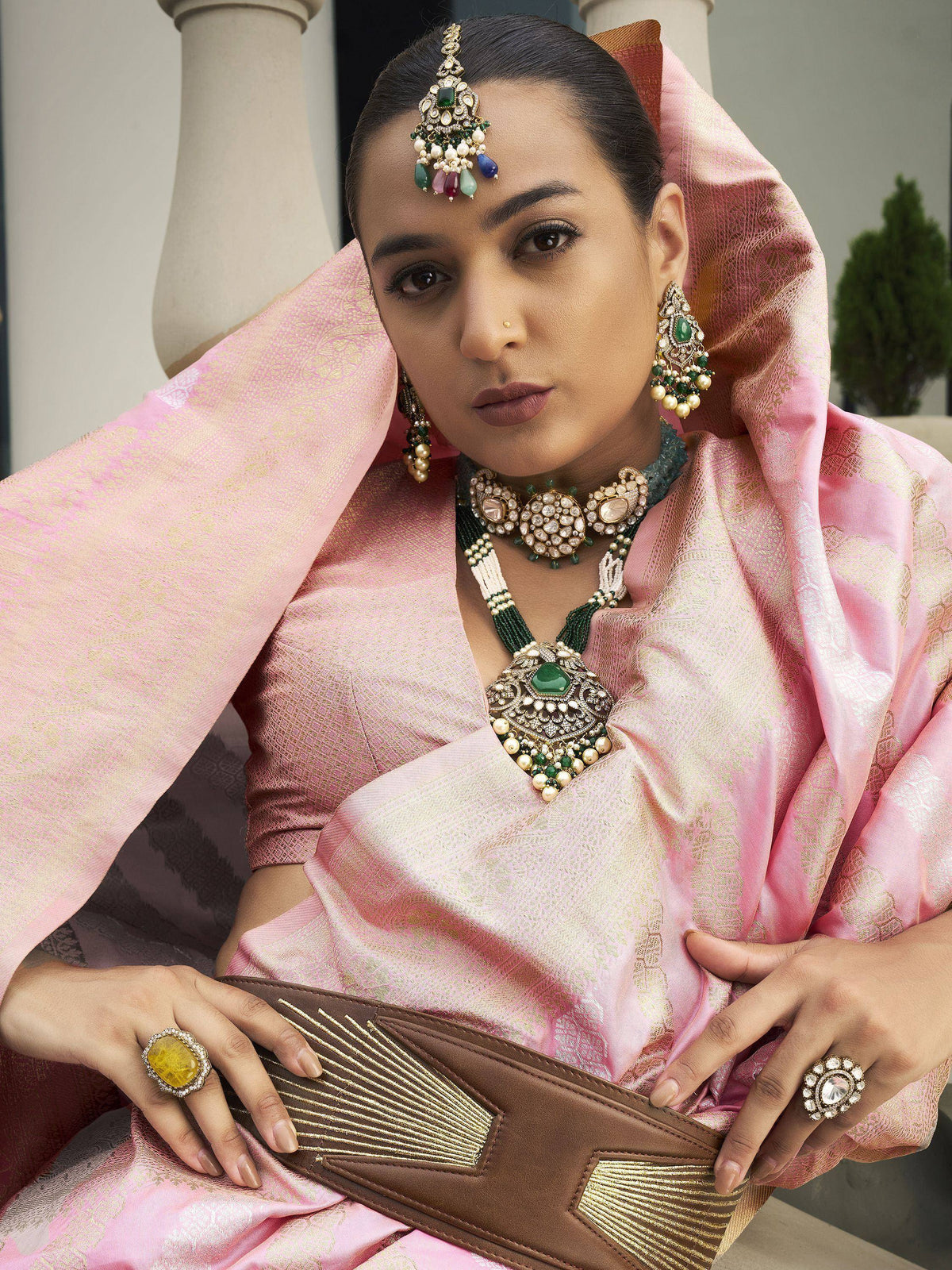 Woman in pink ethnic saree with emerald jewelry and statement rings, traditional Indian attire