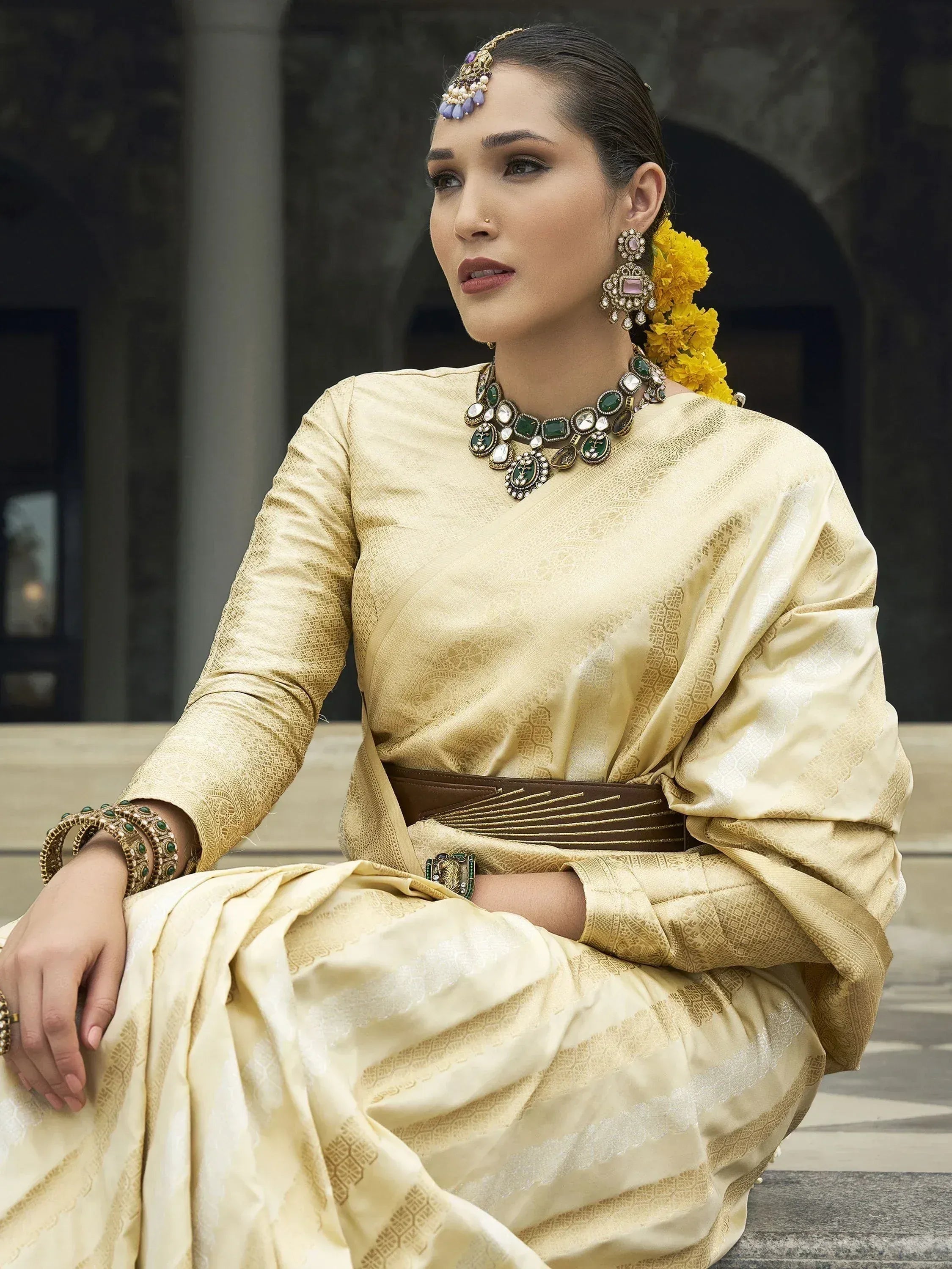 Elegant woman in gold ethnic gown with traditional jewelry and floral hair accessory