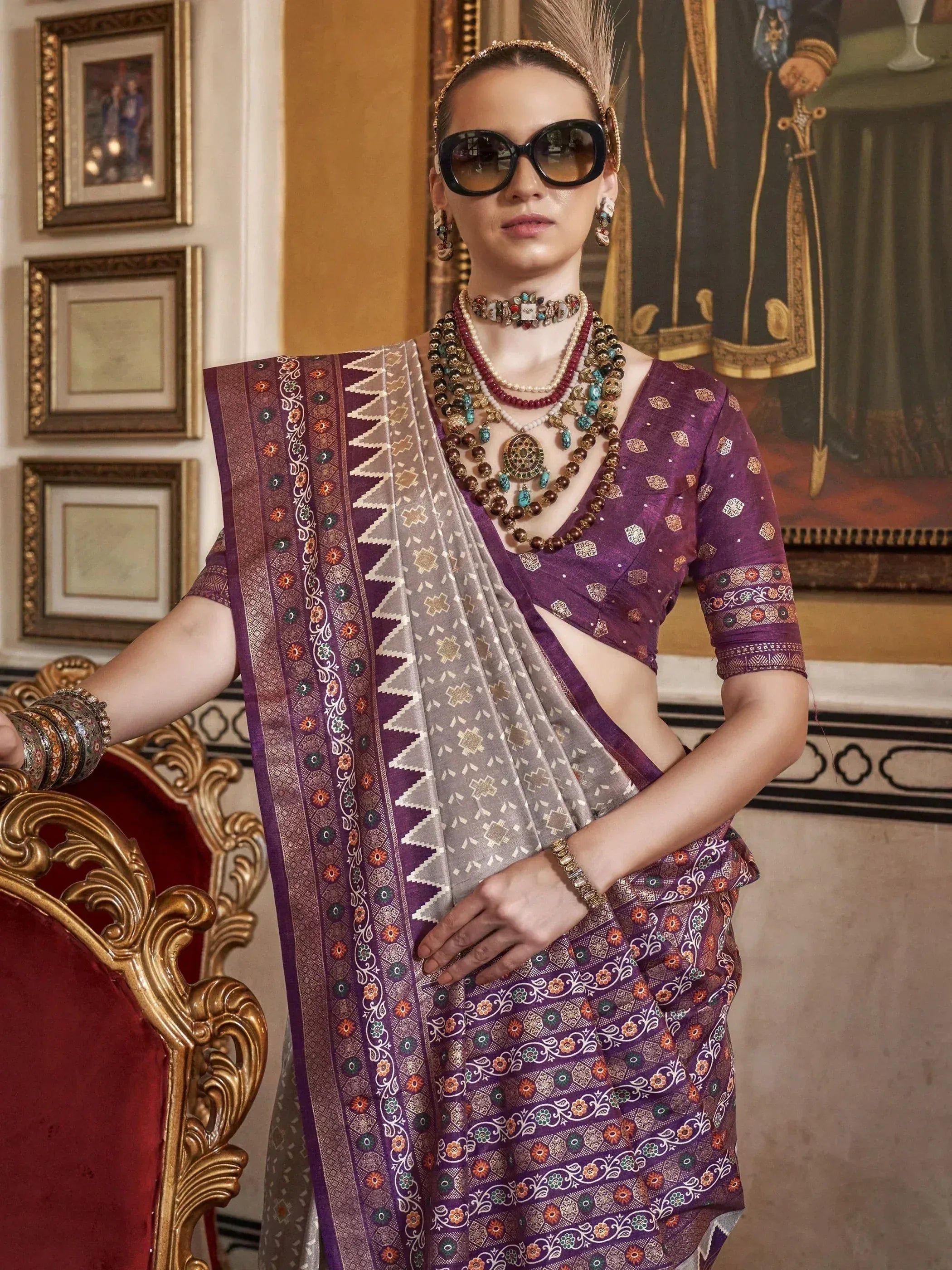 Purple and silver designer saree with intricate embroidery, paired with statement jewelry and sunglasses for a modern ethnic look.