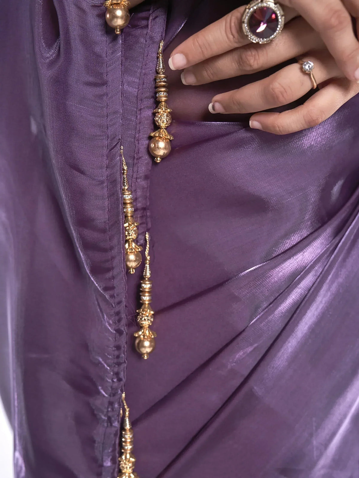 Purple satin ethnic gown with gold tassel buttons and statement rings