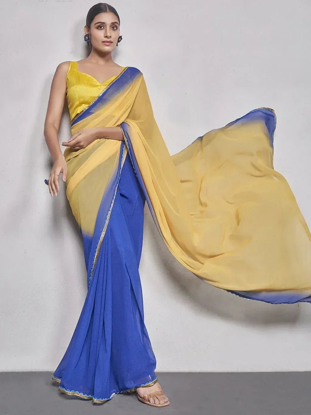 Yellow and blue ombre saree with gold trim, styled with sleeveless blouse for ethnic wear