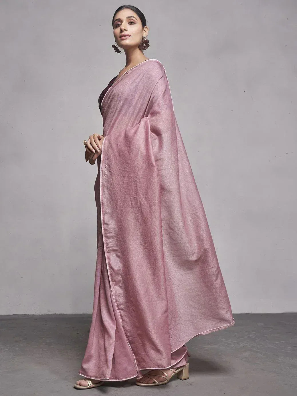 Elegant pink saree with shimmering texture, styled with floral earrings and heels for ethnic occasions