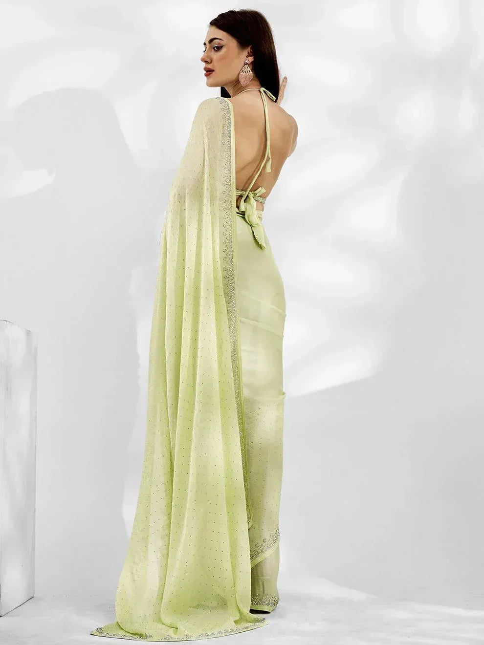 Light green designer saree with backless blouse and embellished border, perfect for ethnic occasions