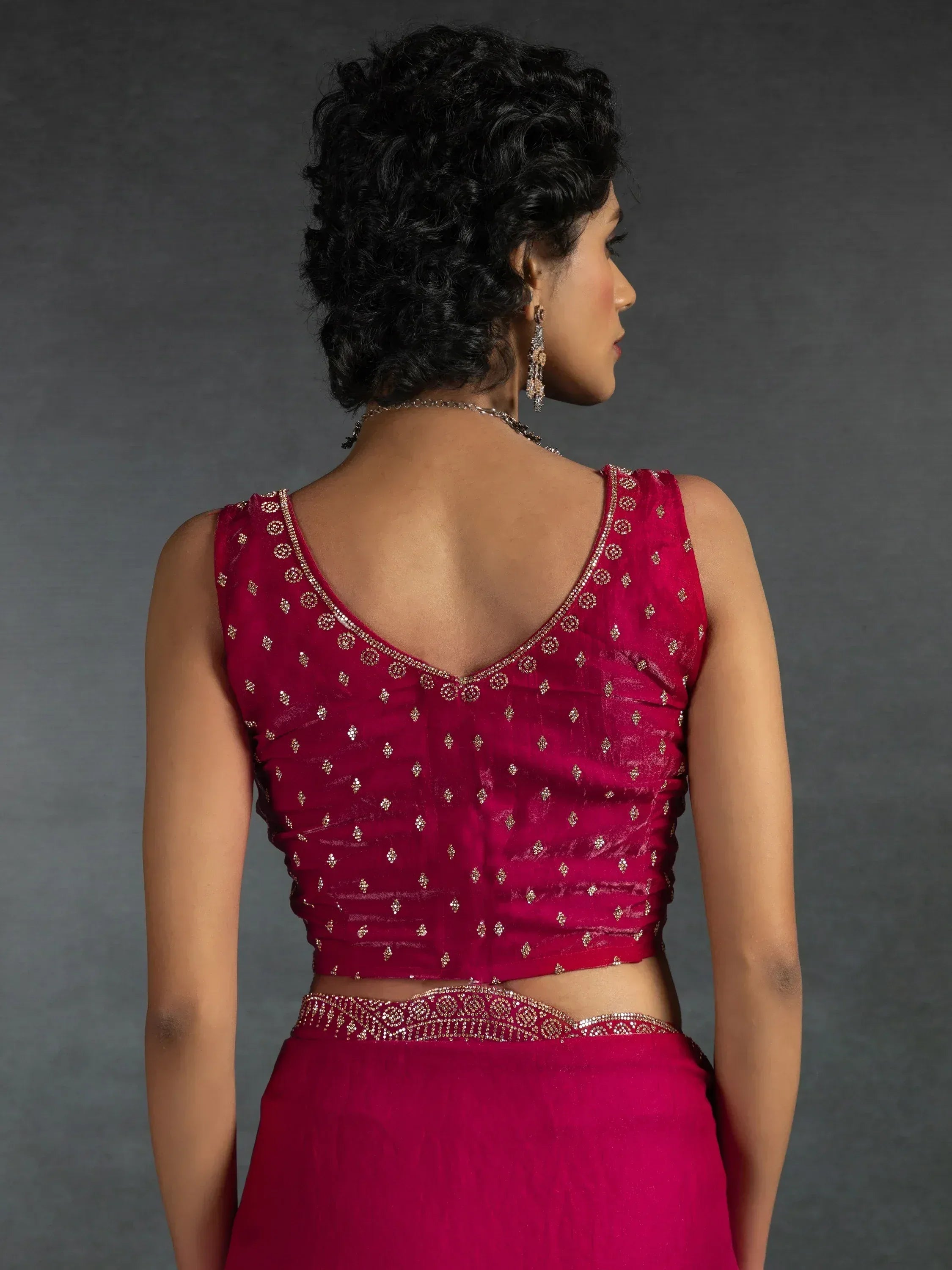 Back view of woman in maroon embroidered lehenga choli with gold embellishments, perfect for ethnic occasions.
