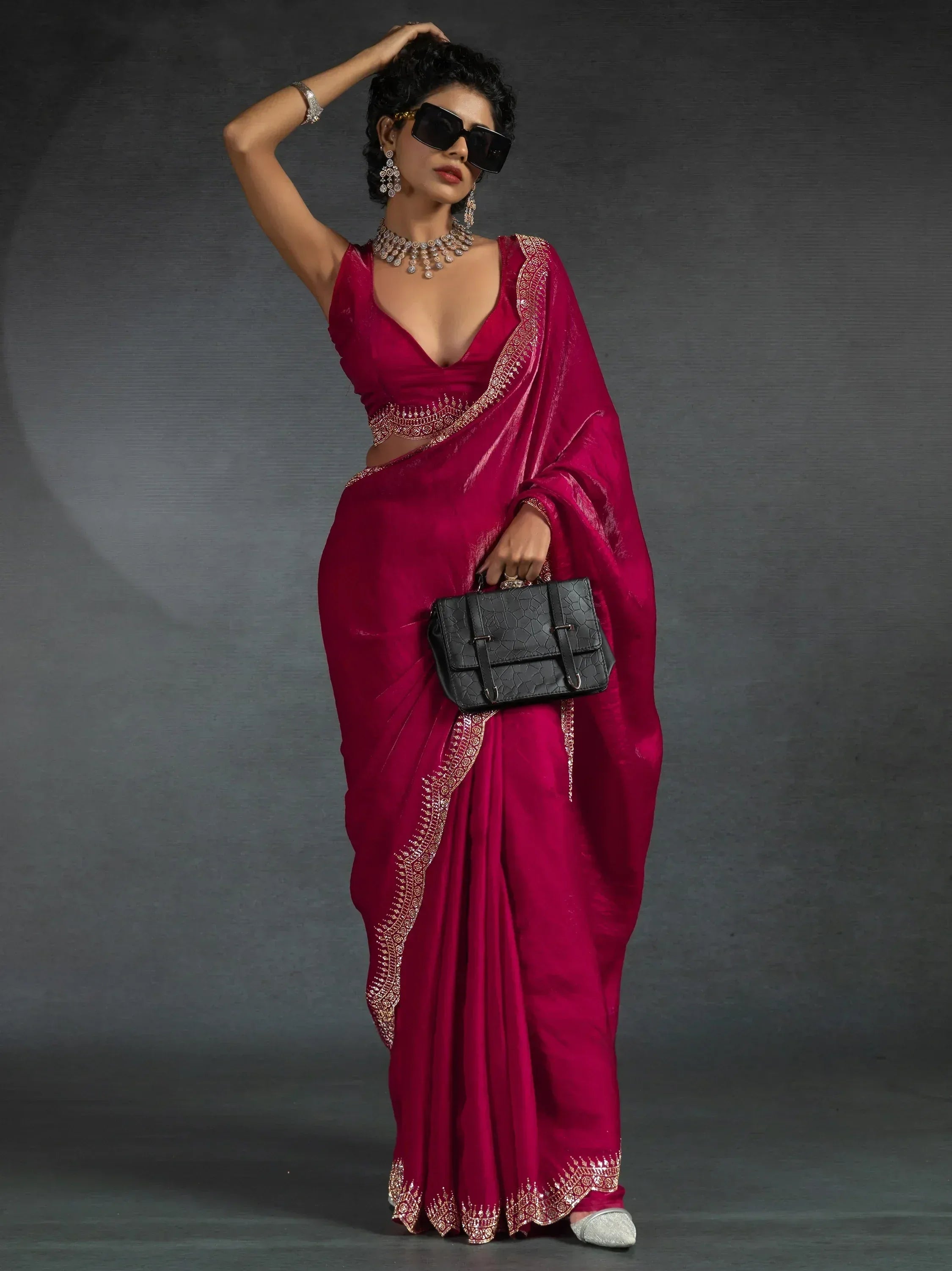 Elegant maroon saree with gold embroidery, paired with statement jewelry and a black clutch.