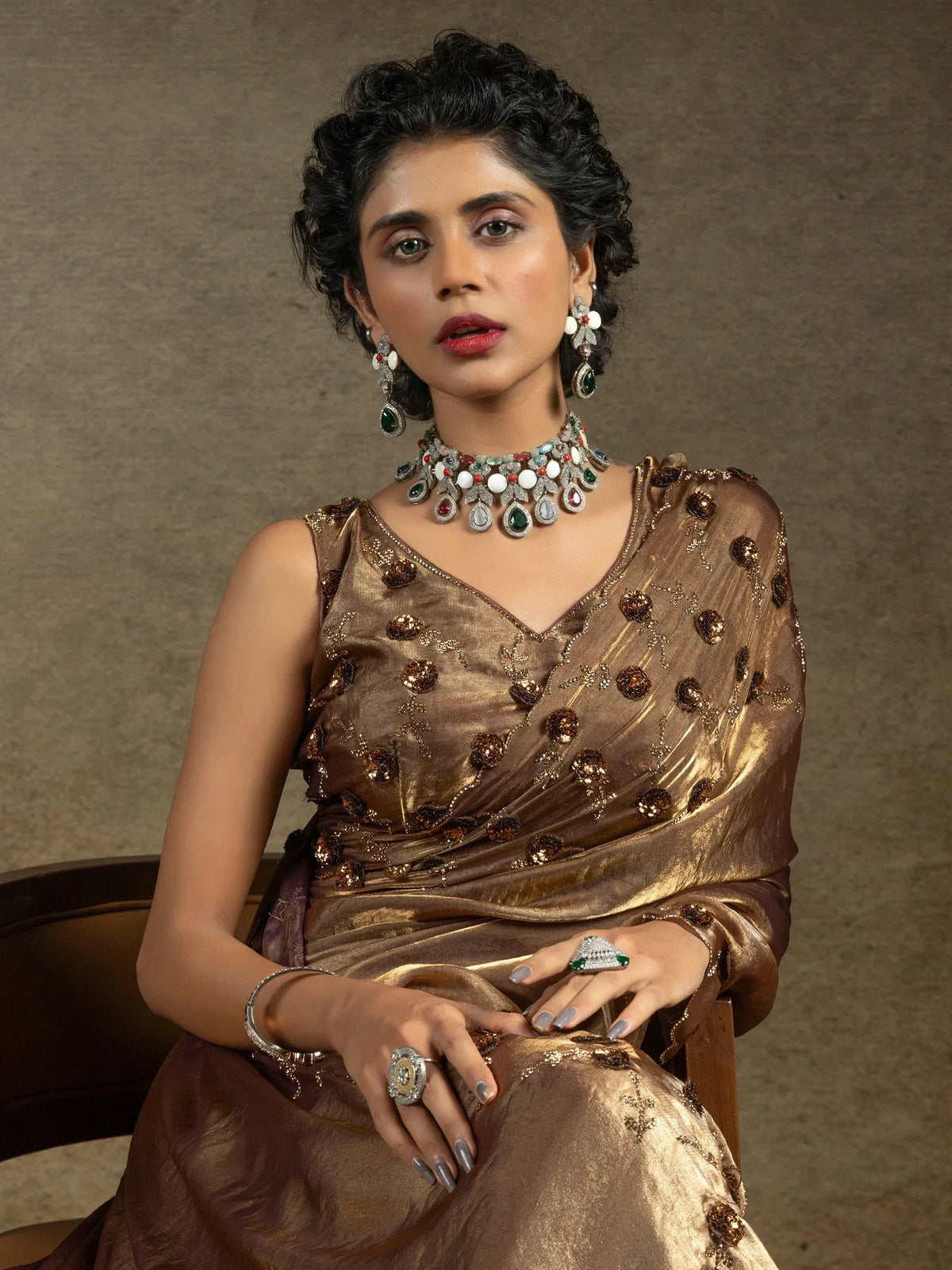 Elegant woman in golden ethnic saree with intricate embroidery and gemstone jewelry