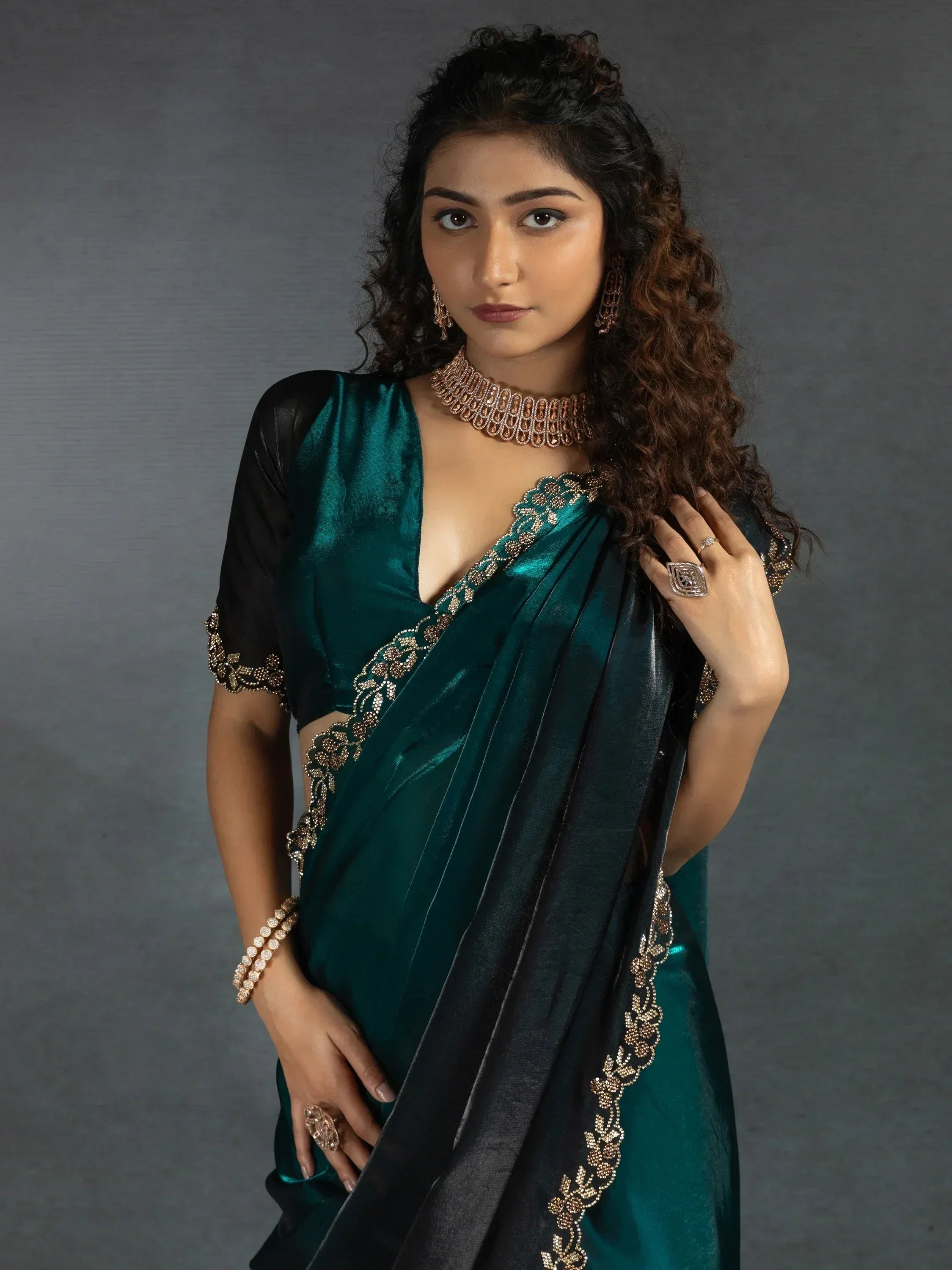 Emerald green velvet saree with gold embroidery and black blouse, styled with traditional jewelry