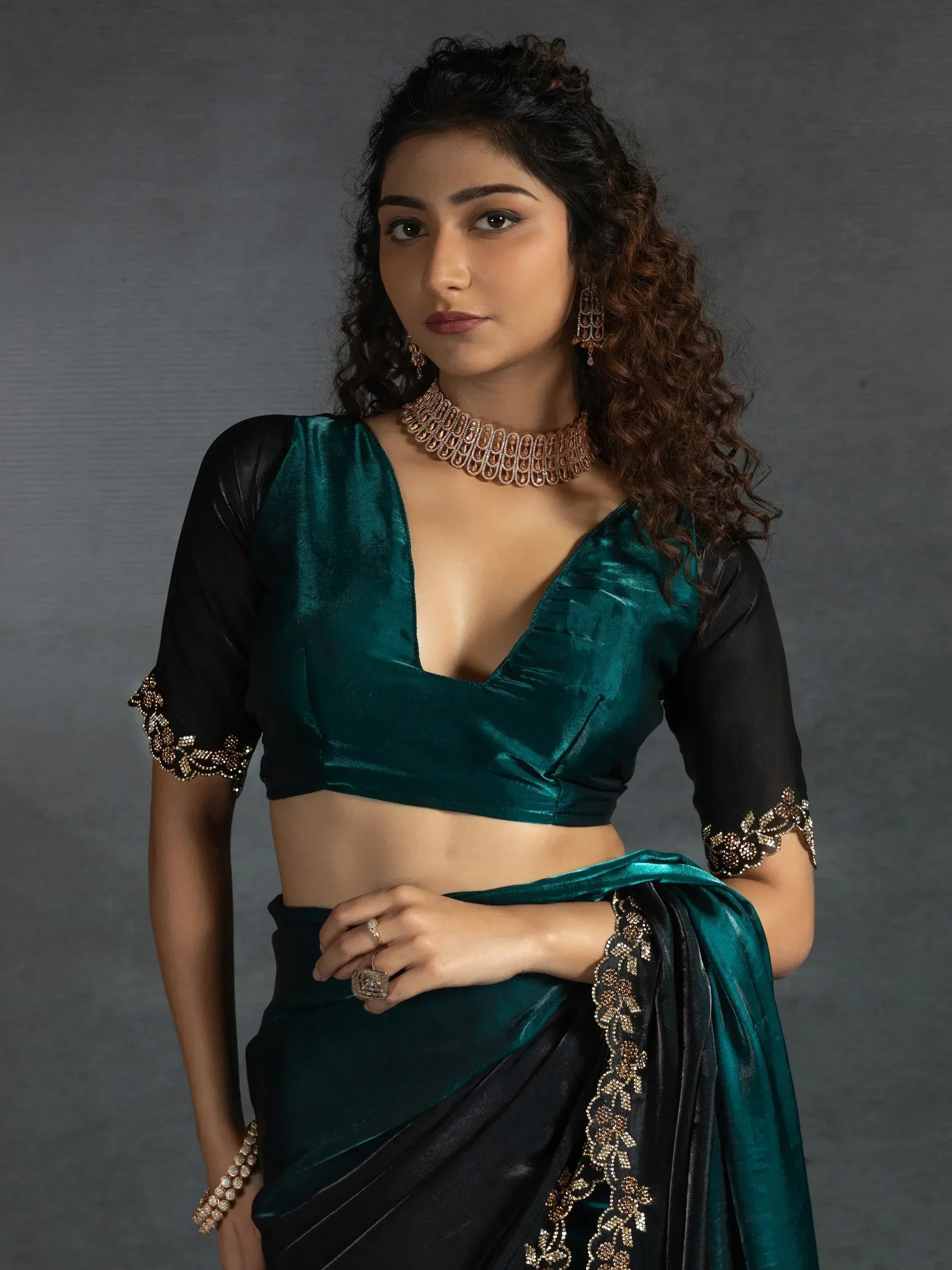 Emerald green velvet saree with black blouse and gold embroidery, styled with statement jewelry