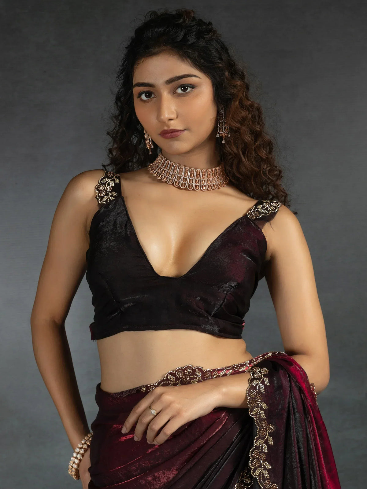 Elegant maroon and black saree with gold embroidery, paired with a designer blouse and jewelry