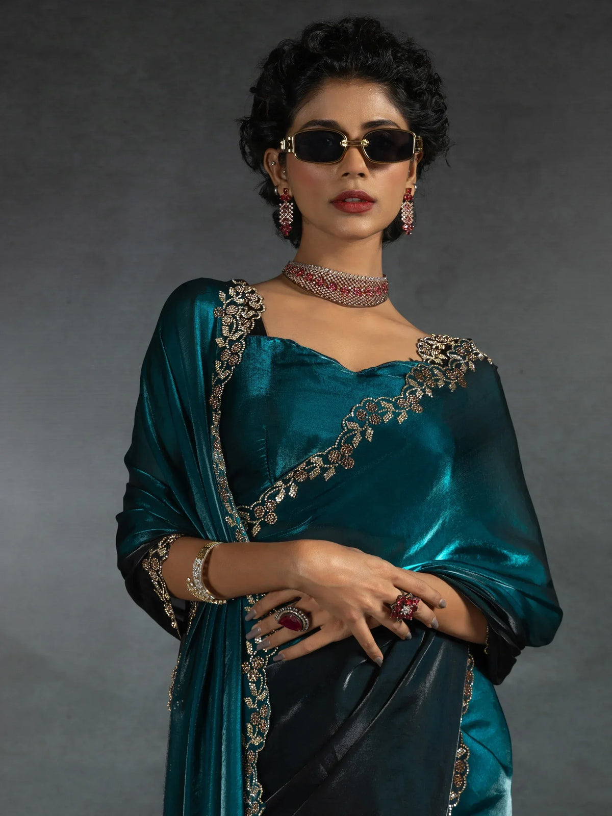 Elegant teal saree with gold embroidery, paired with statement jewelry and sunglasses