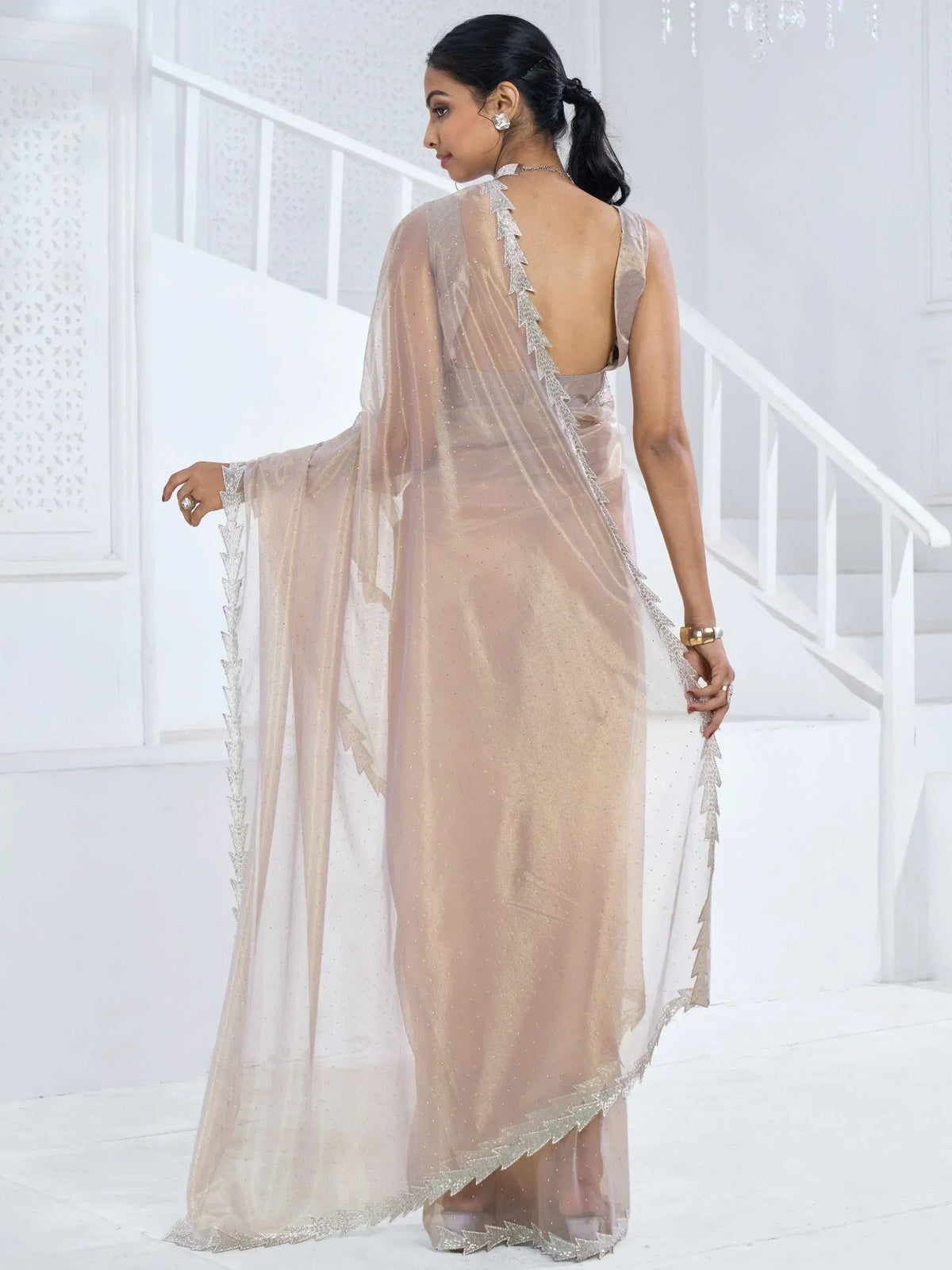 Elegant beige saree with silver embroidery, sheer cape, and open back design for festive occasions