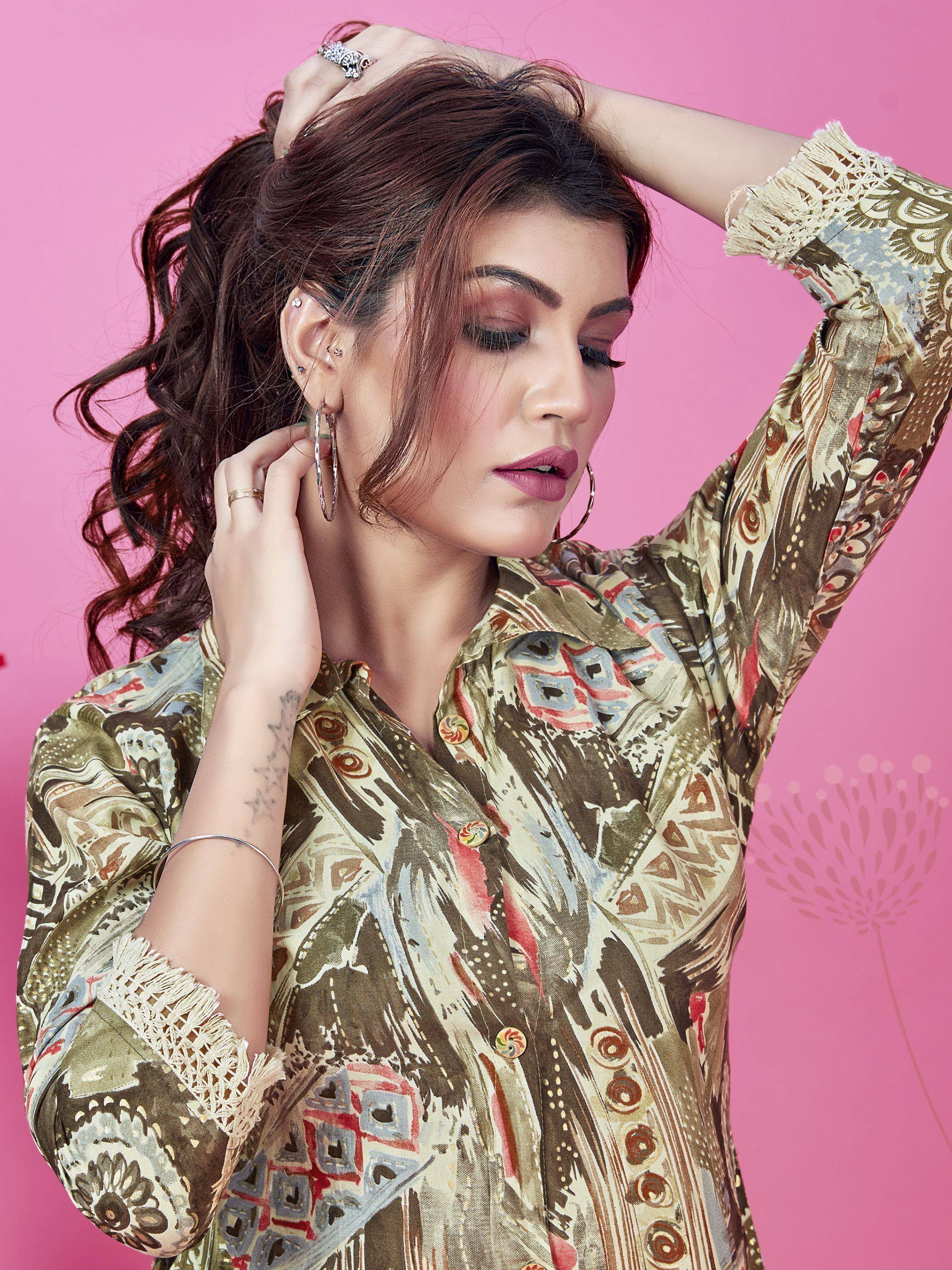Woman in printed ethnic kurta with lace cuffs, hoop earrings, and rings against pink background