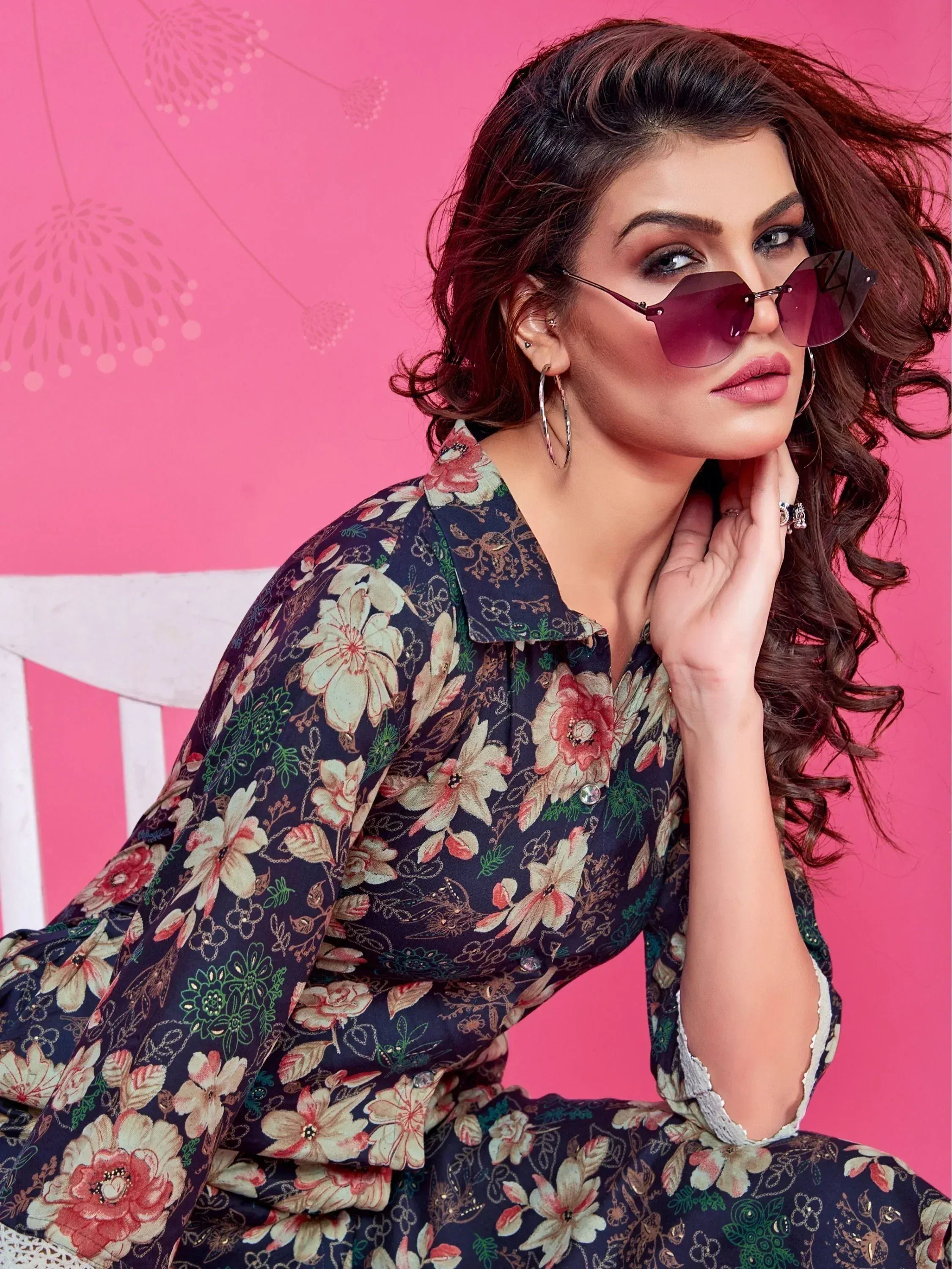 Woman in floral print ethnic gown with sunglasses, pink background