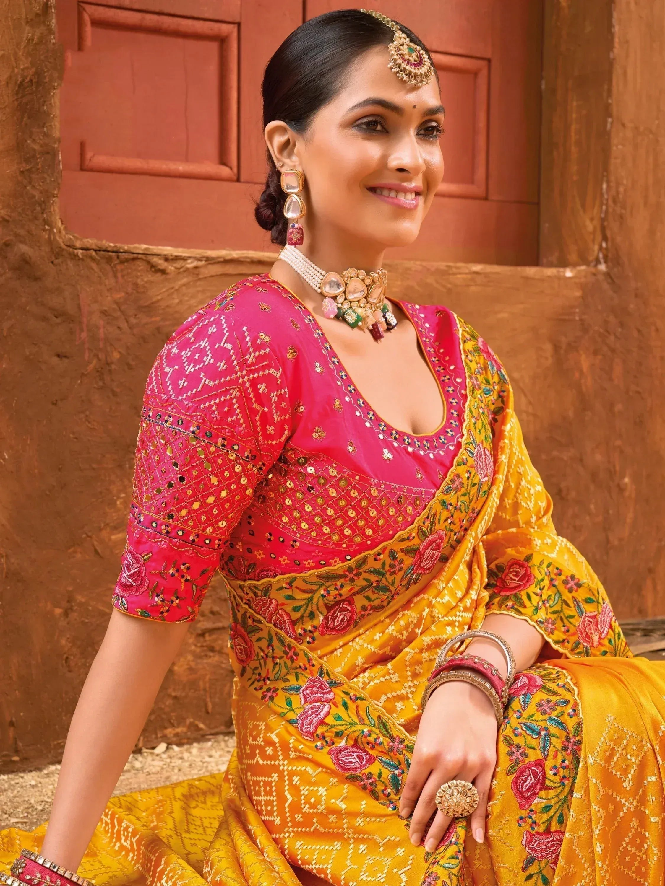 Woman in vibrant yellow floral saree with pink embroidered blouse, traditional Indian ethnic wear