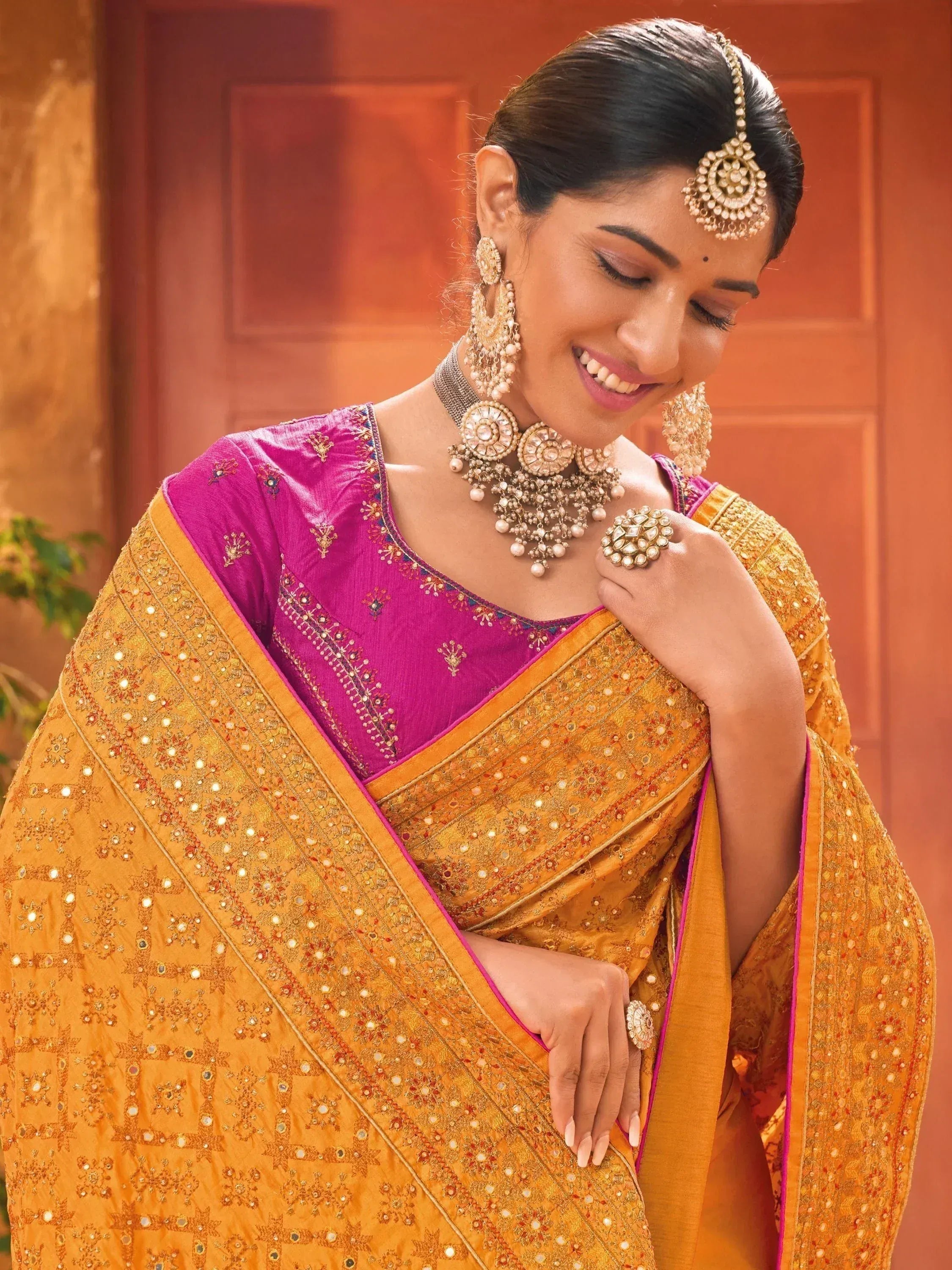 Woman in vibrant yellow embroidered saree with pink blouse, traditional Indian jewelry, perfect for festive occasions