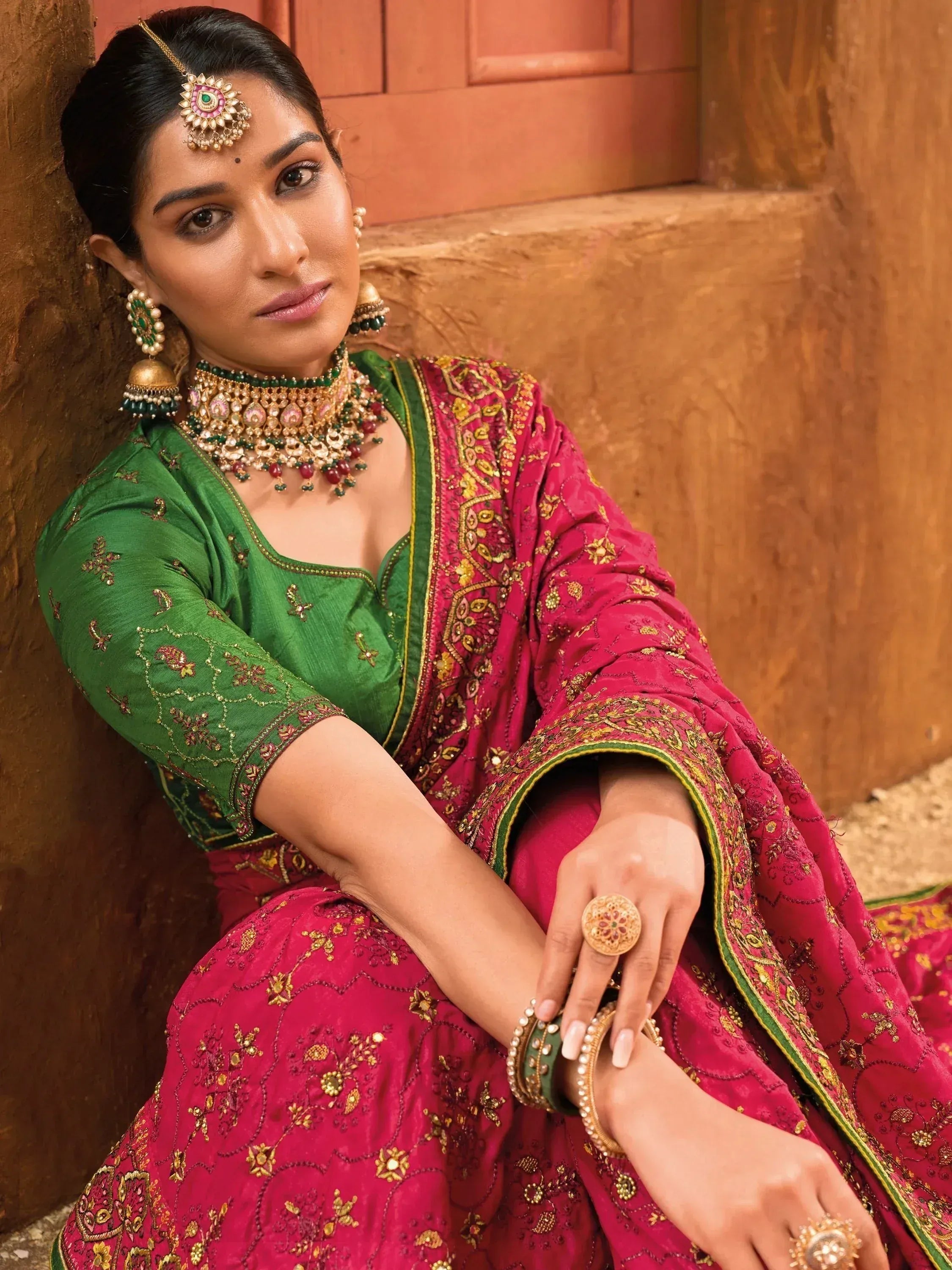 Woman in green and pink embroidered lehenga choli with traditional Indian jewelry