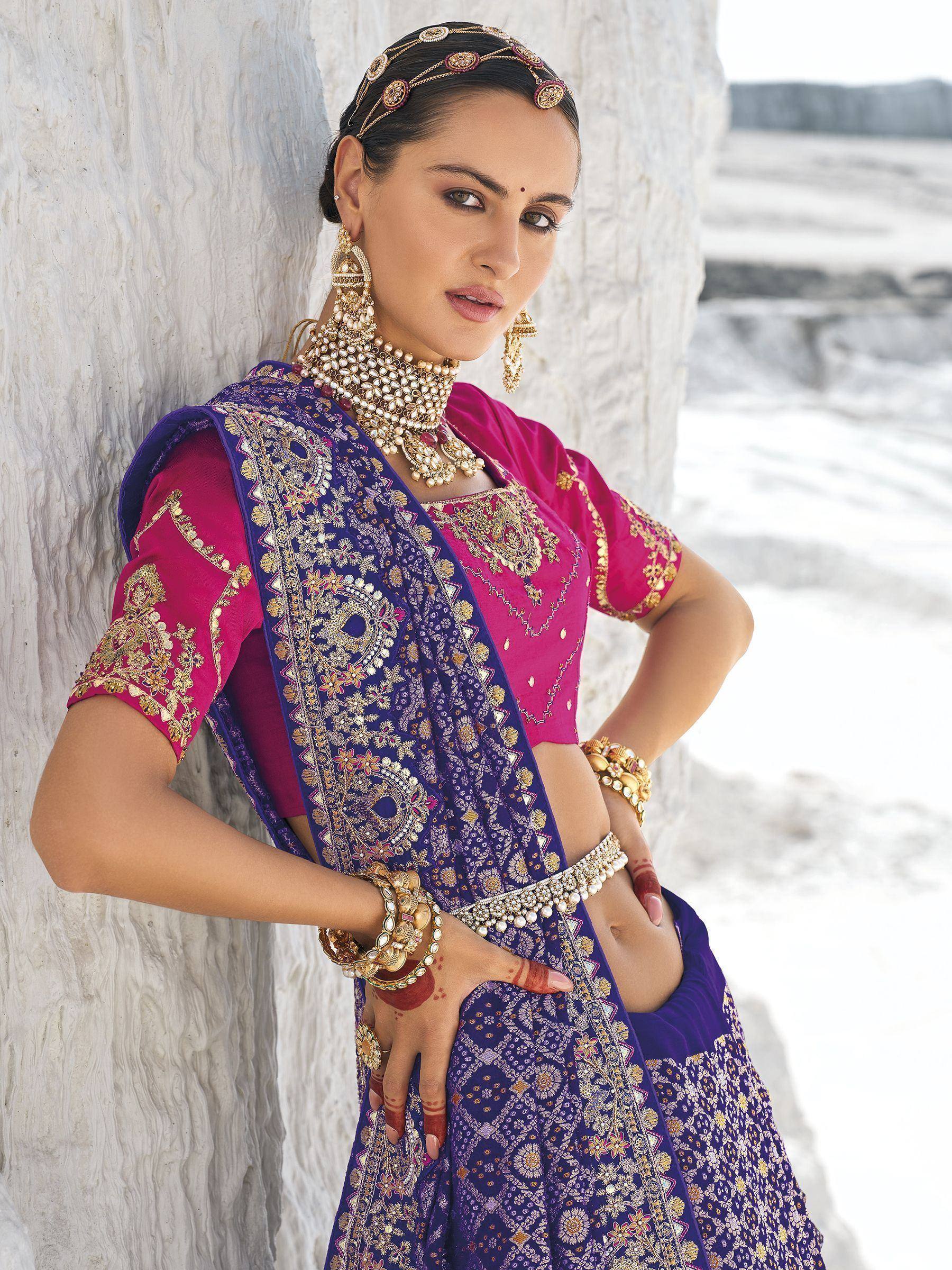 Woman in purple and pink embroidered lehenga choli with gold jewelry, traditional Indian ethnic wear
