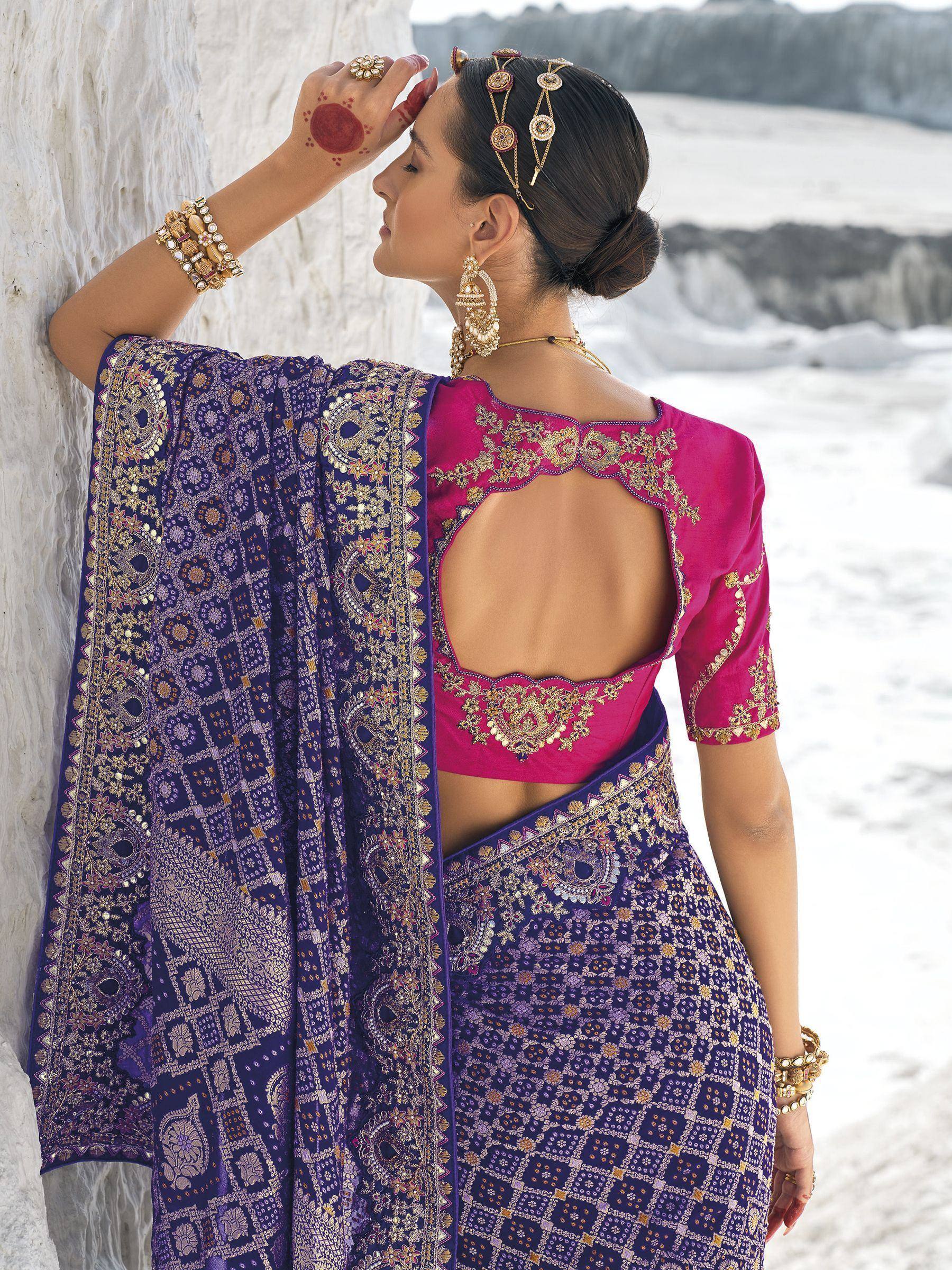Purple and pink embroidered lehenga choli with open back, gold jewelry, and traditional Indian bridal accessories