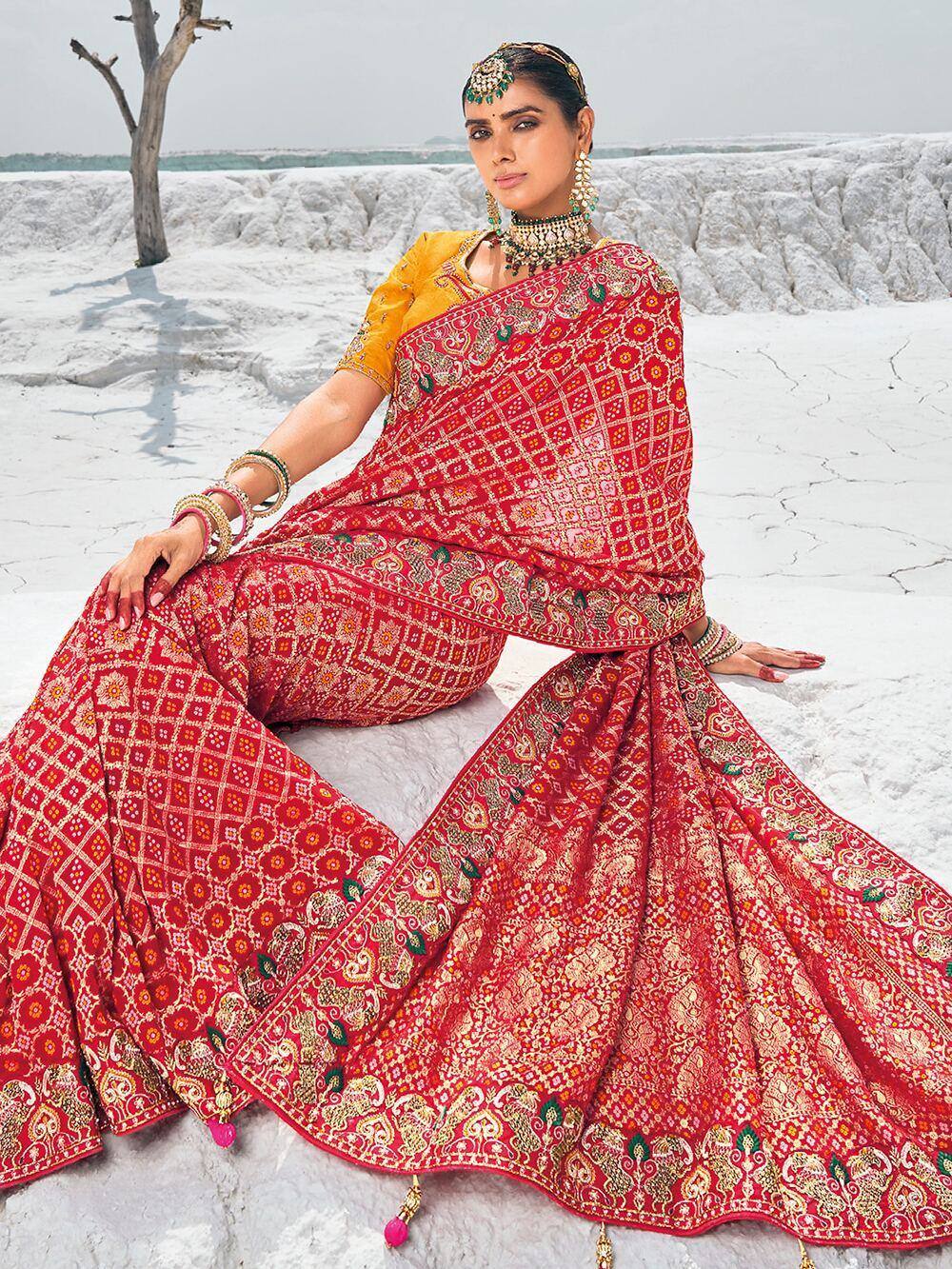 Red embroidered saree with gold patterns, paired with yellow blouse, styled for Indian ethnic wear