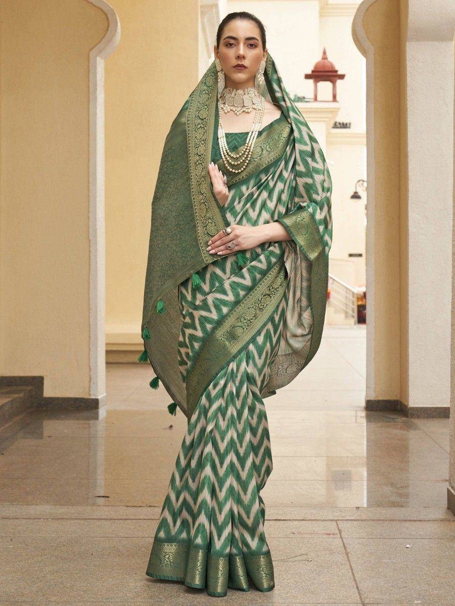 Green and cream zigzag patterned saree with gold border and tassels, styled with traditional jewelry