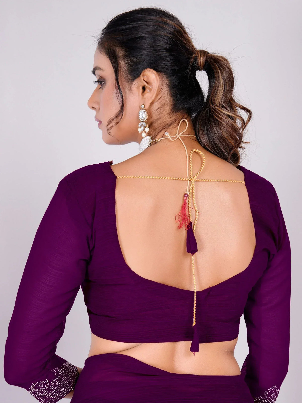 Purple ethnic blouse with open back, tassels, and gold detailing, paired with statement earrings