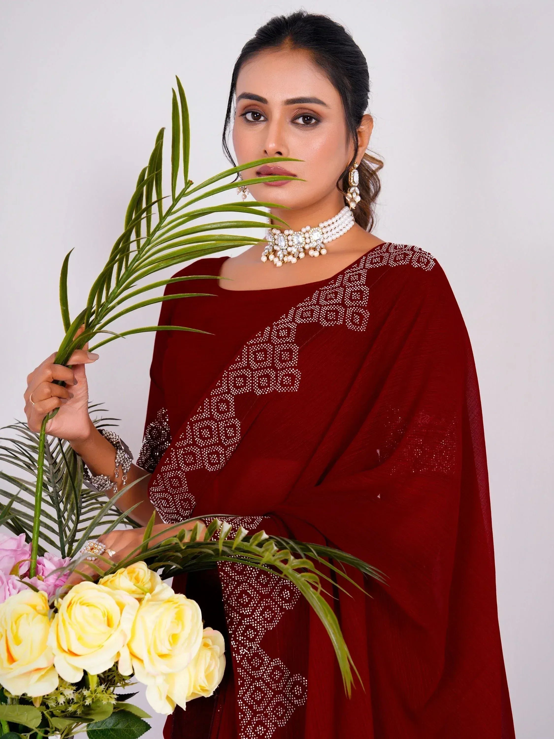 Maroon ethnic gown with white embroidery, paired with pearl jewelry and holding flowers