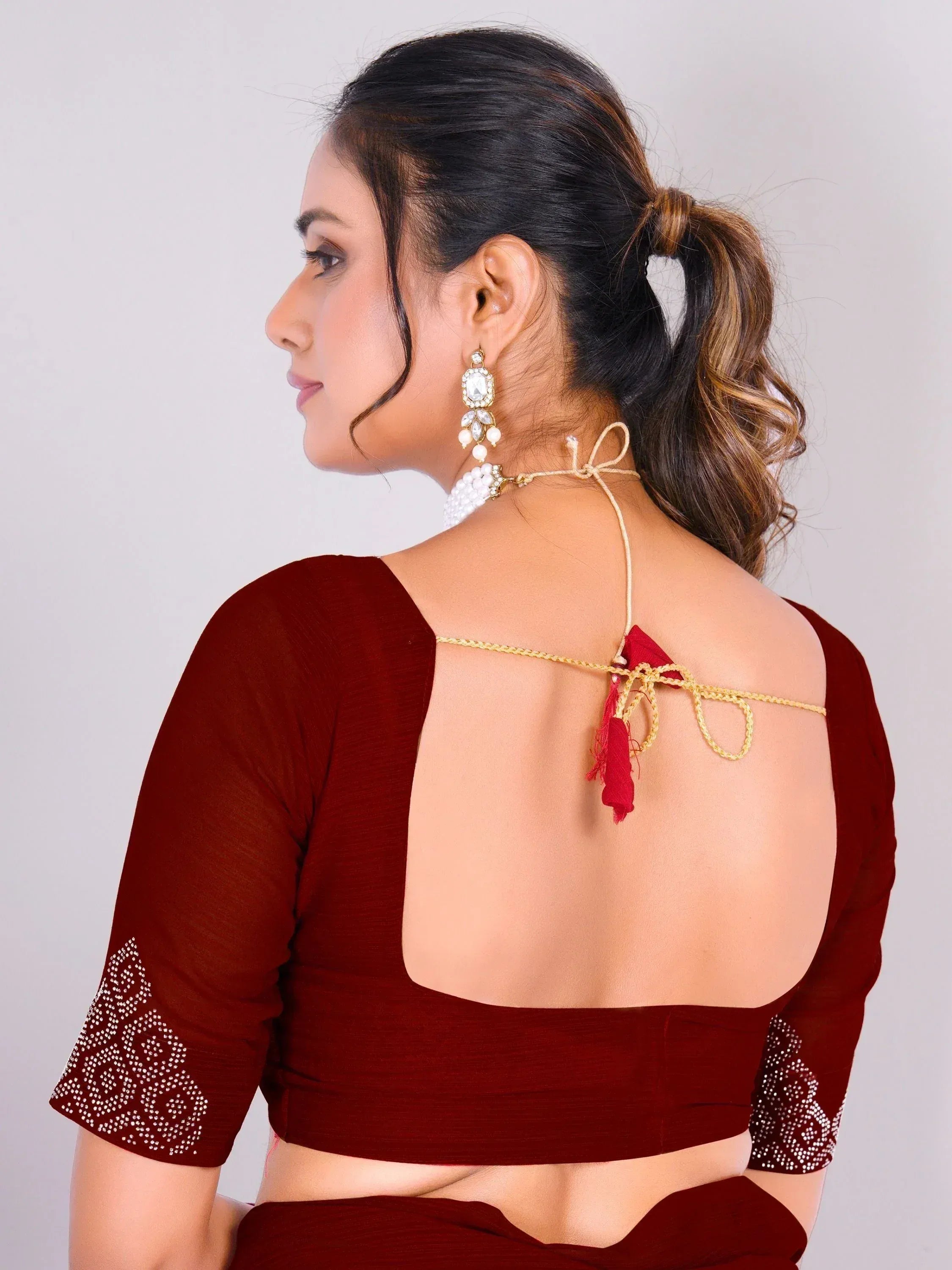 Maroon saree blouse with open back, gold ties, and pearl embroidery for Indian ethnic wear
