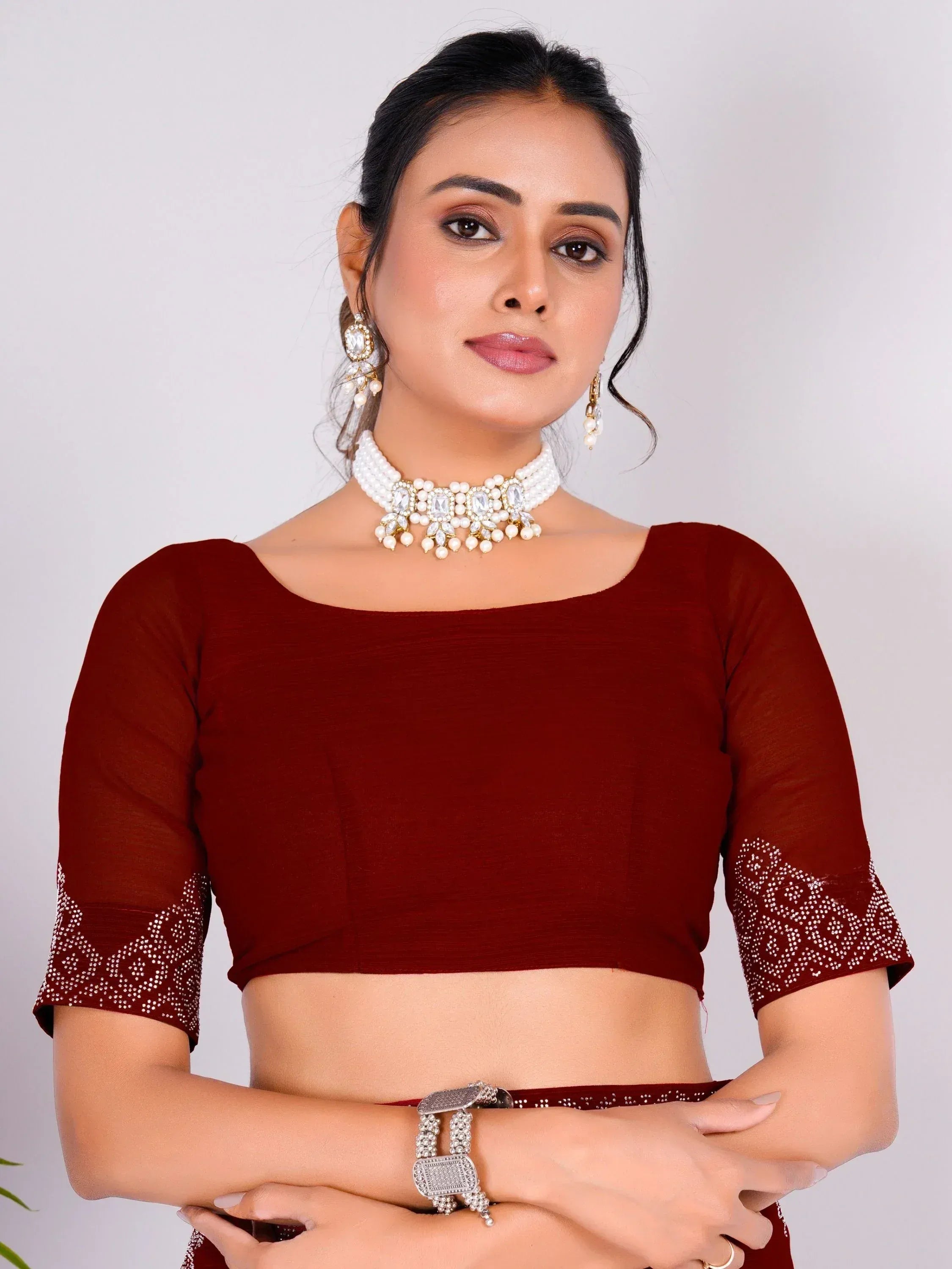 Maroon ethnic crop top with embellished sleeves, paired with pearl and stone jewelry for Indian wear