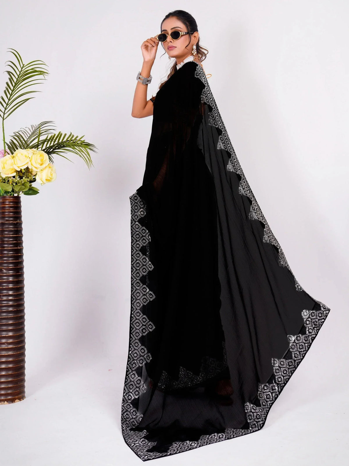 Black ethnic gown with silver embroidery, styled with sunglasses and jewelry for festive occasions
